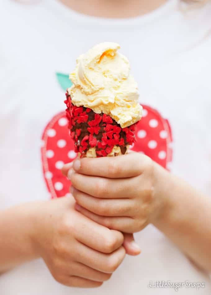 Child holding a decorated ice cream cone filled with vanilla ice cream