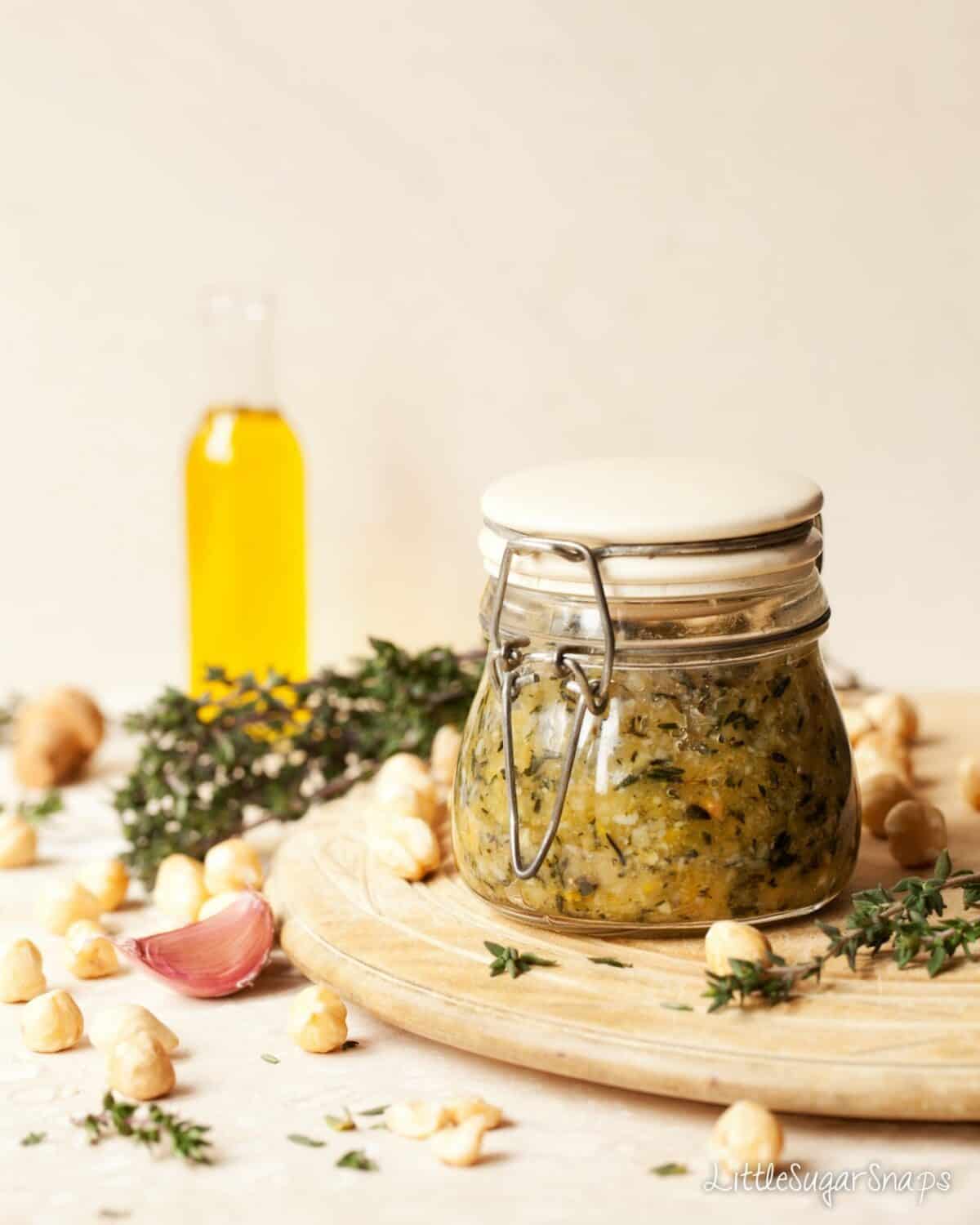 A jar of homemade hazelnut and thyme pesto on a wooden board