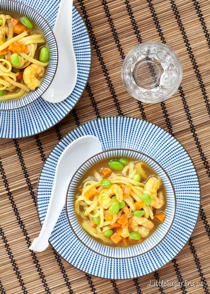 A bowl of Katsu Curry soup with noodles, prawns, edamames and carrots