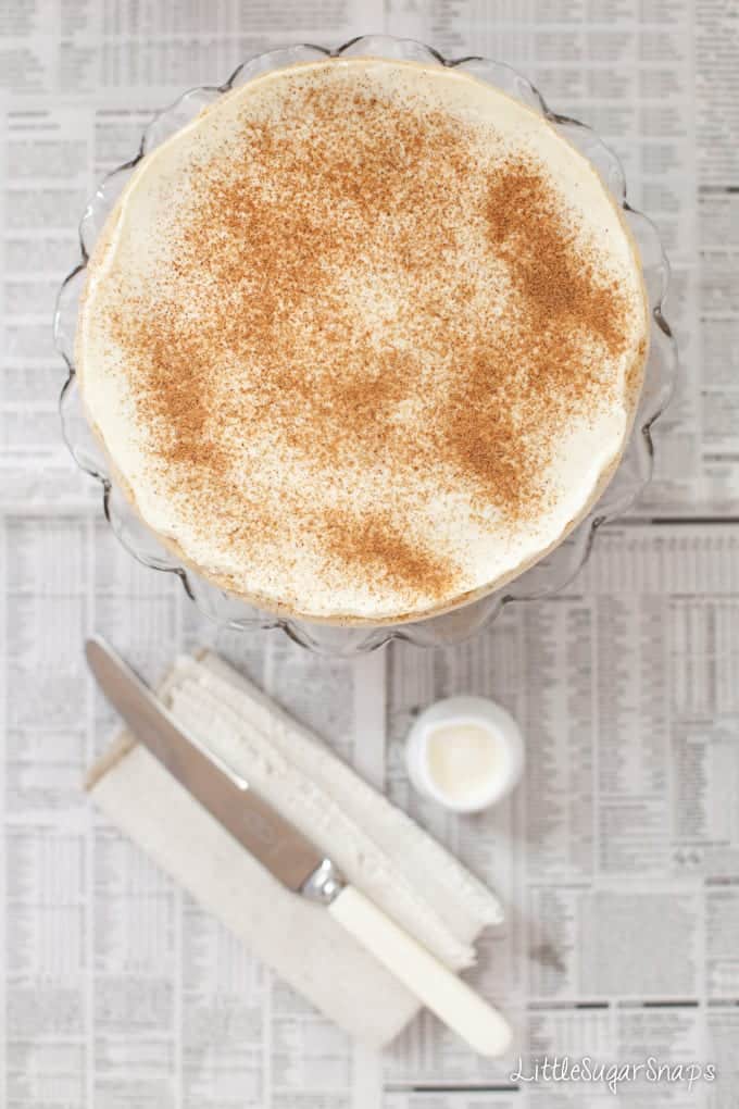 uncut rrange & Rum Cheesecake  dusted with spice on a cakestand.