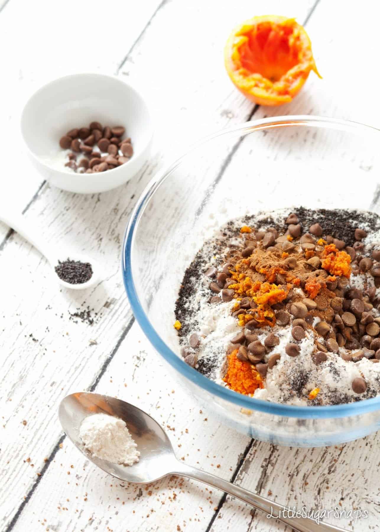 Dry ingredients for muffins in a mixing bowl: flour, orange zest, chocolate chips