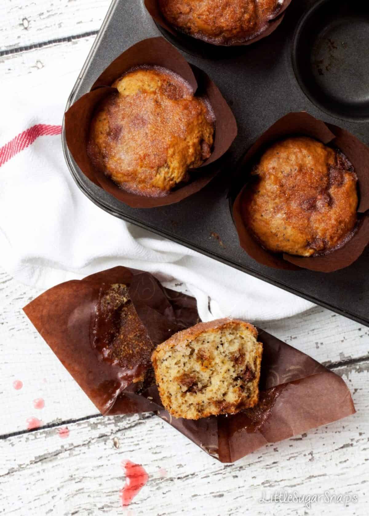 A tin of Orange Drizzle Muffins with one part eaten on the table.