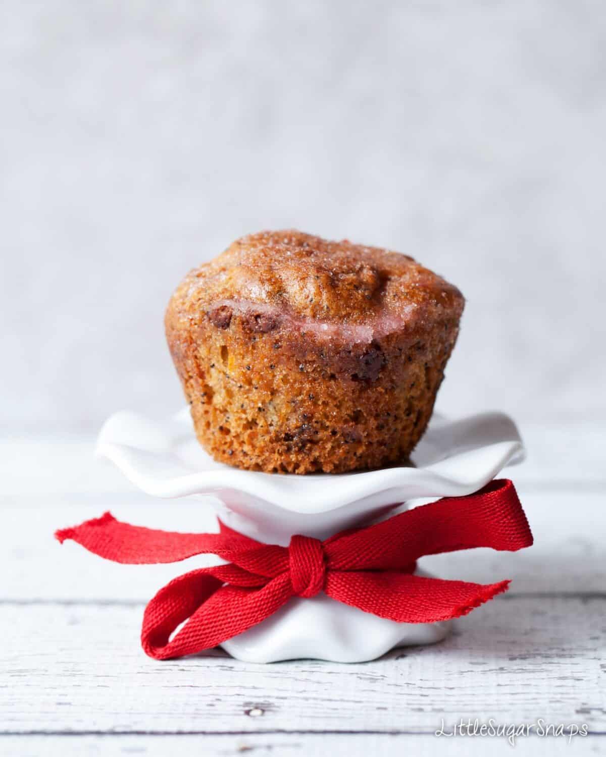 Orange Drizzle Muffin on a small cake stand with a red ribbon.