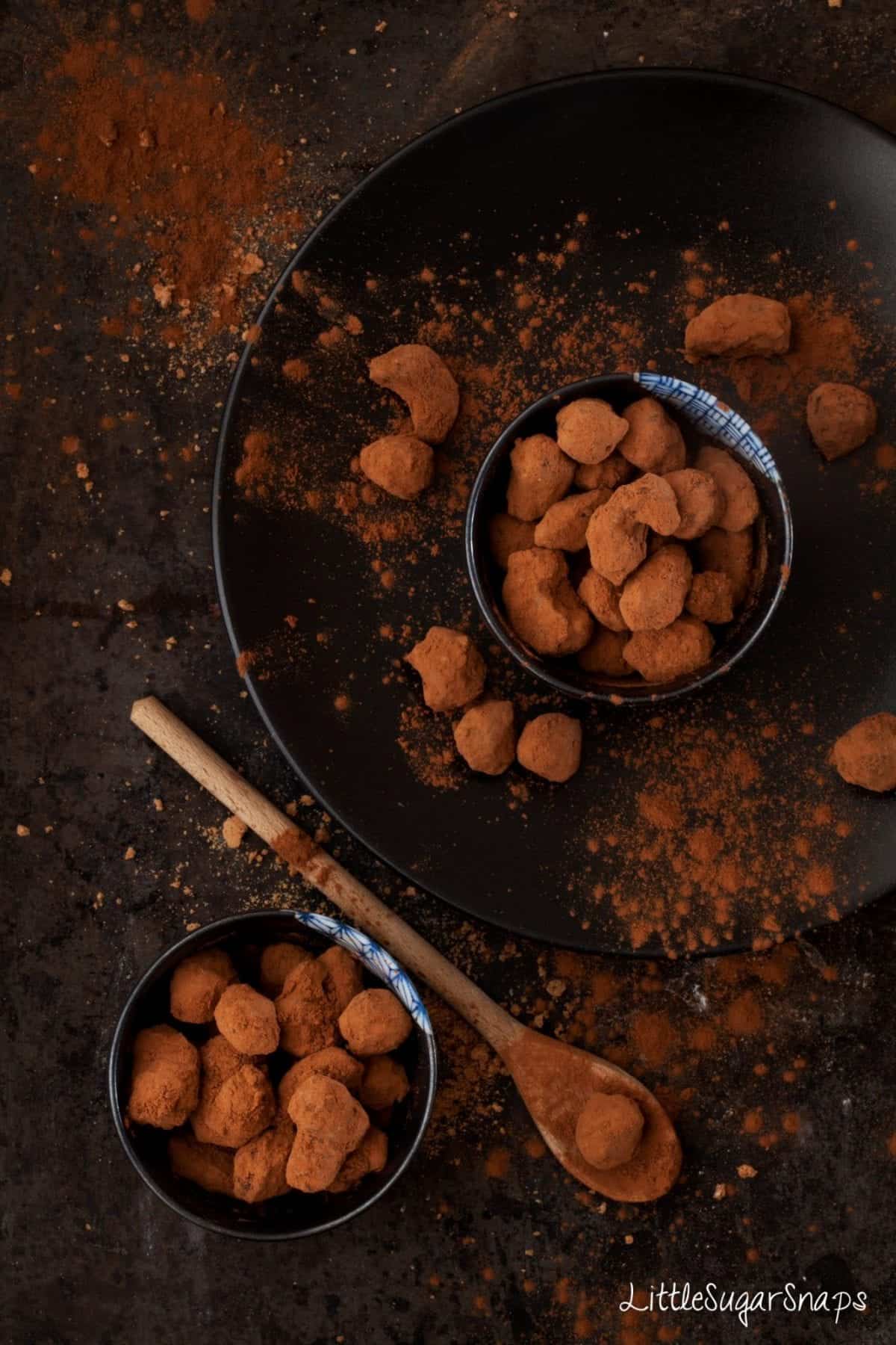 Chocolate covered nuts dusted in cocoa powder in small bowls. 