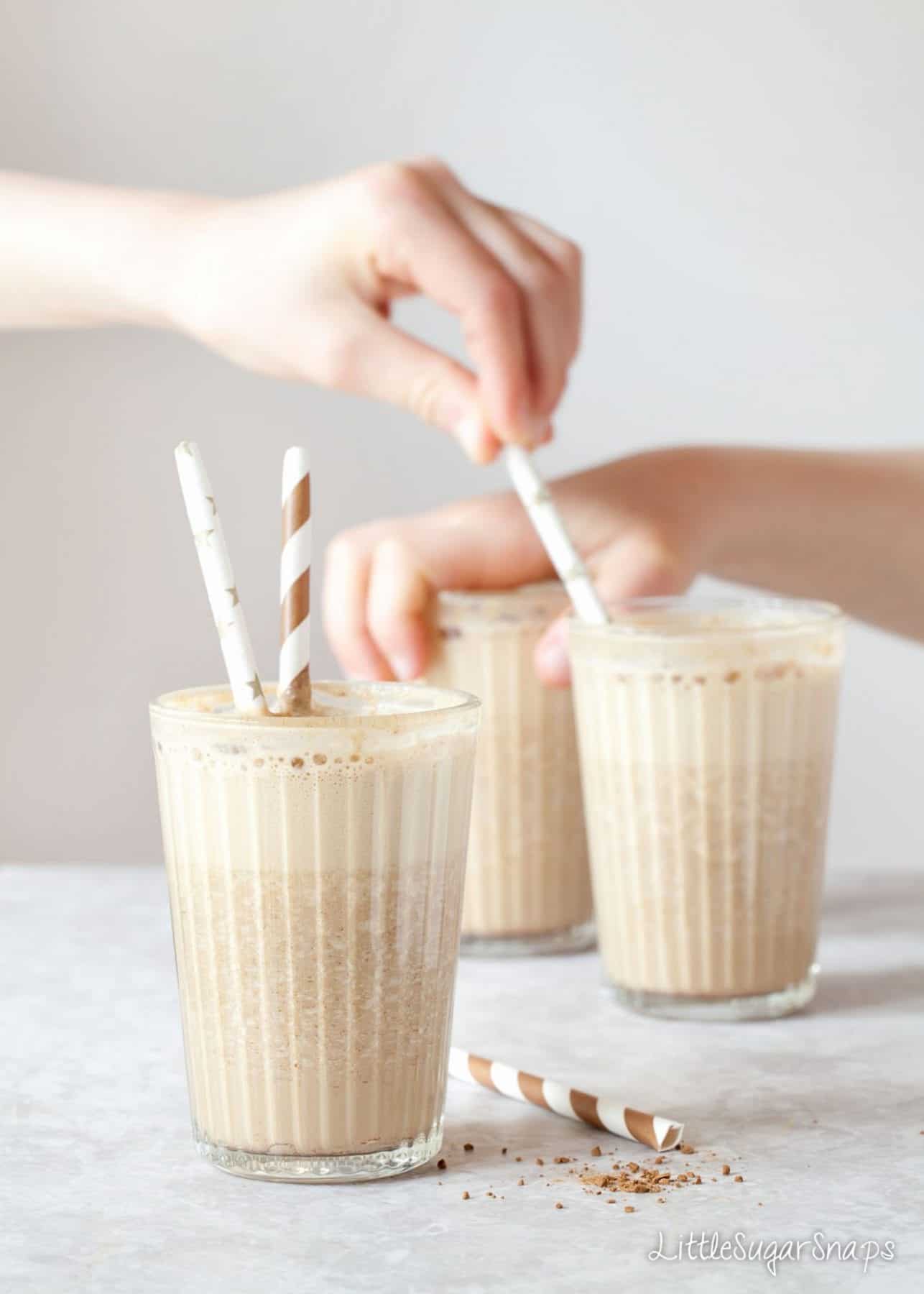 Coffee date shakes in glasses with children poking papers straws into the glasses 