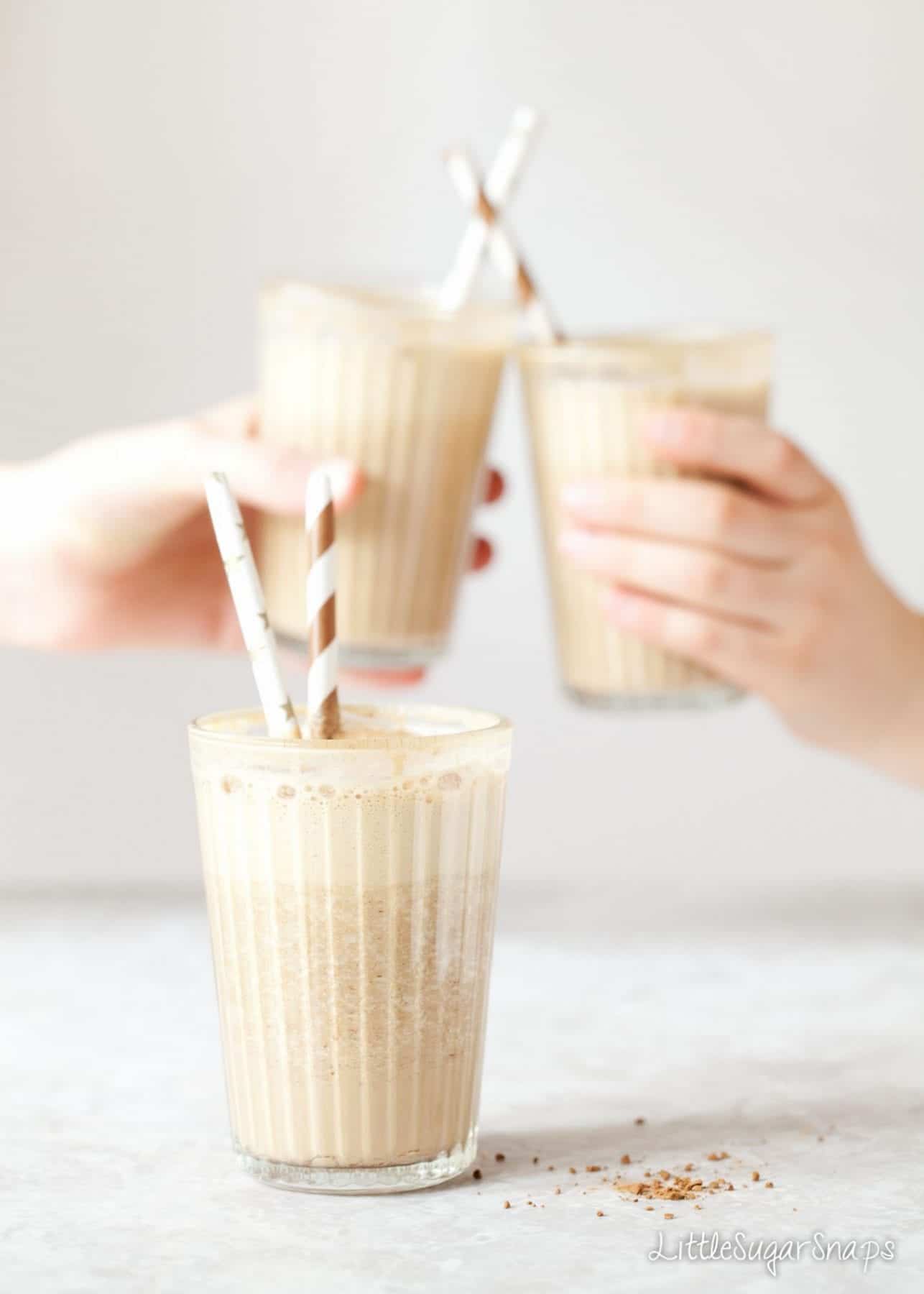 Children chinking glasses of coffee date shake together in a 'cheers' motion.