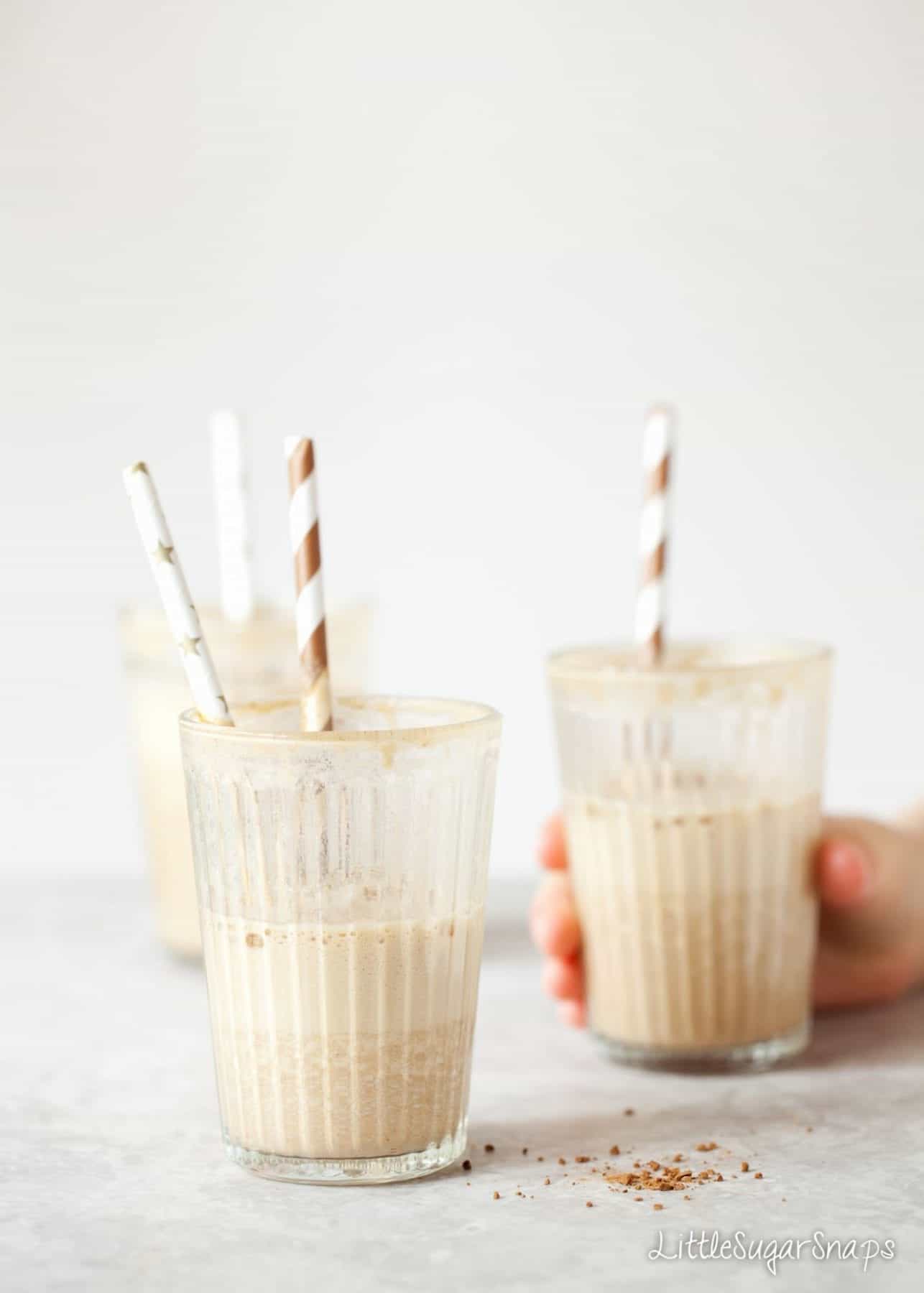 Half consumed Date Shakes in glasses with a childs hand around one.
 