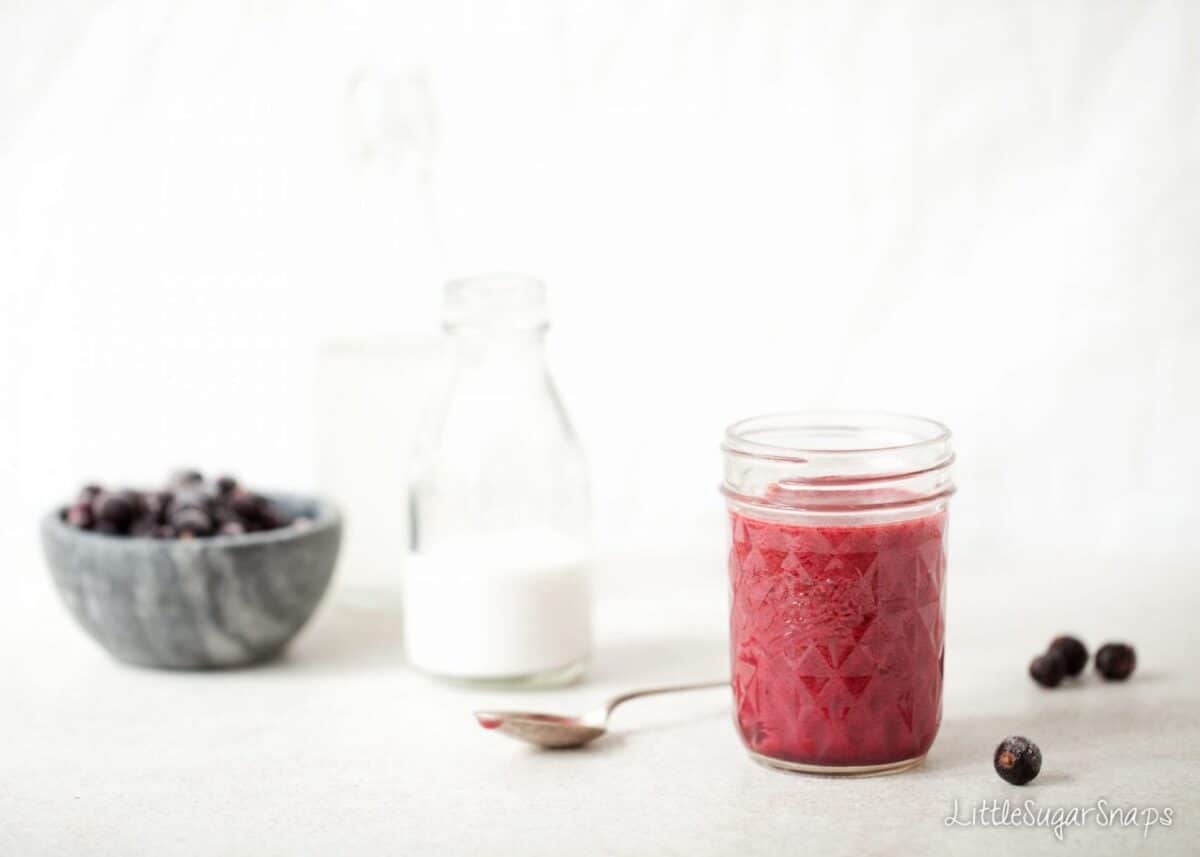 Smoothie in a jam jar with blackcurrants and coconut milk