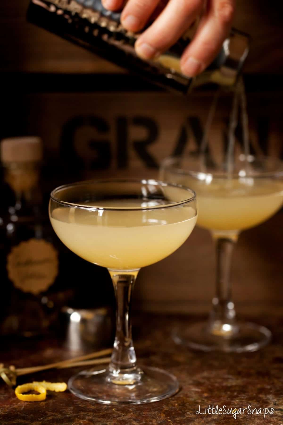 Person pouring a pear cocktail into glasses