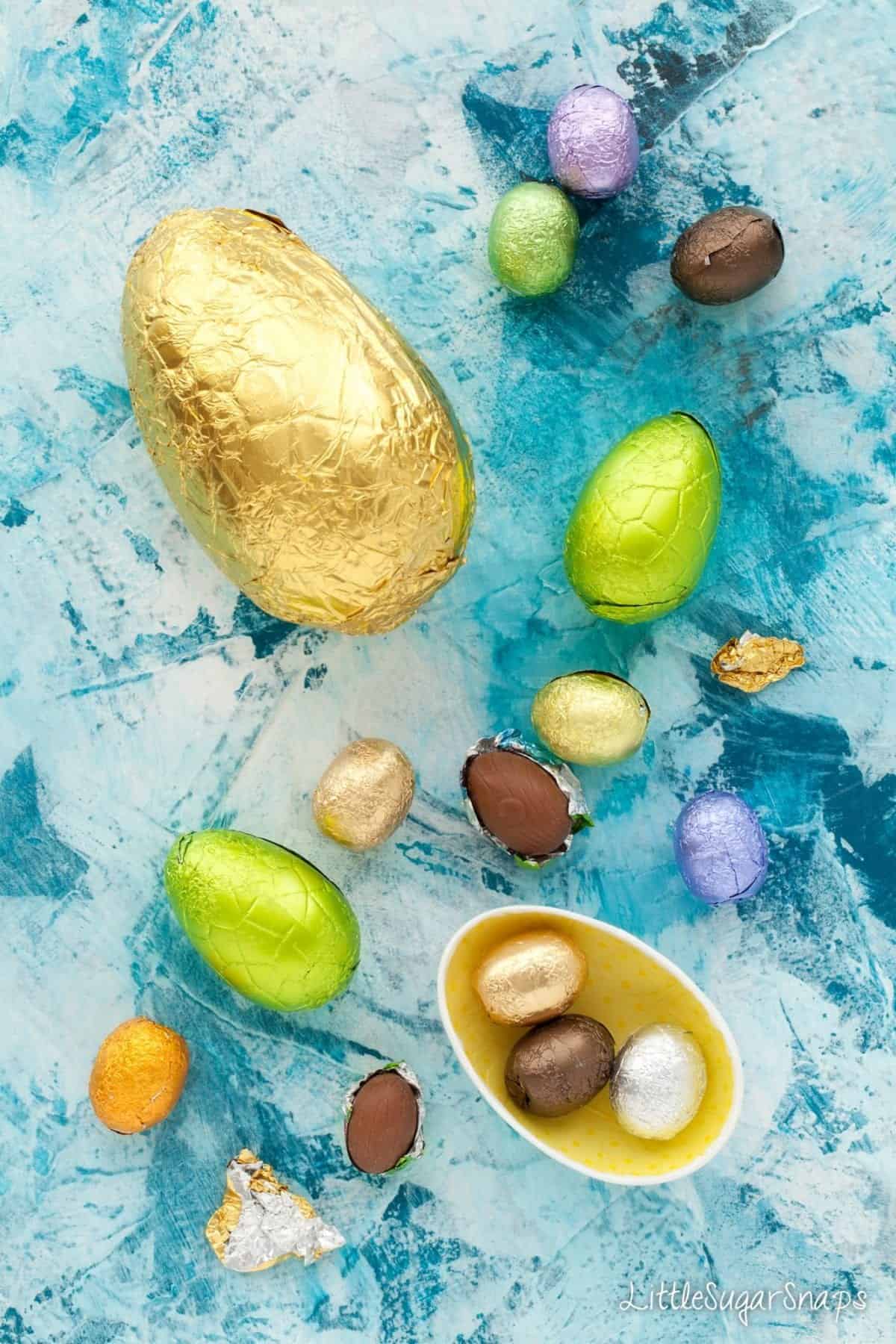 Various foil wrapped chocolate eggs on a blue tabletop