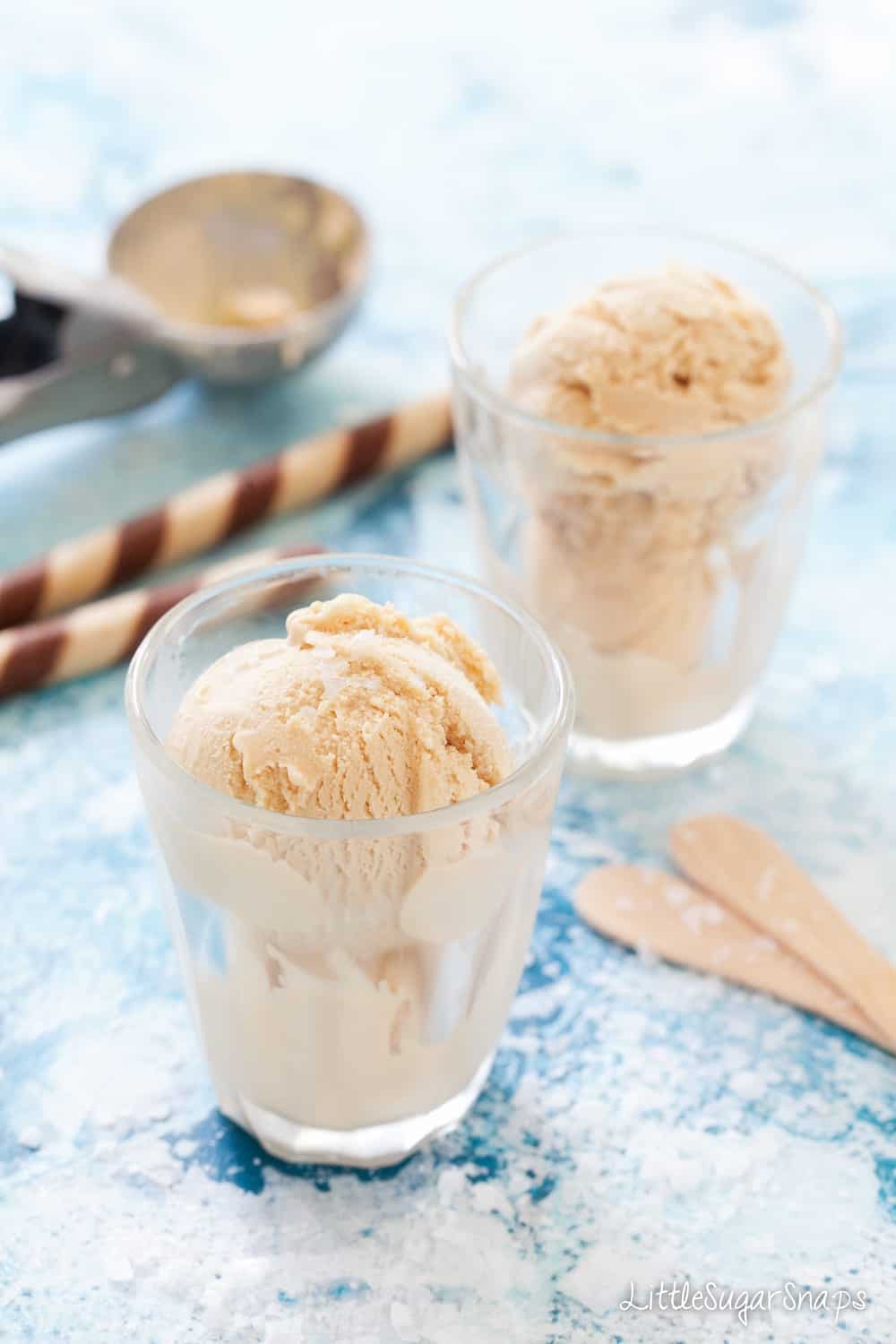 Salted Caramel Ice Cream in small glasses with wooden spoons and chocolate wafers in shot