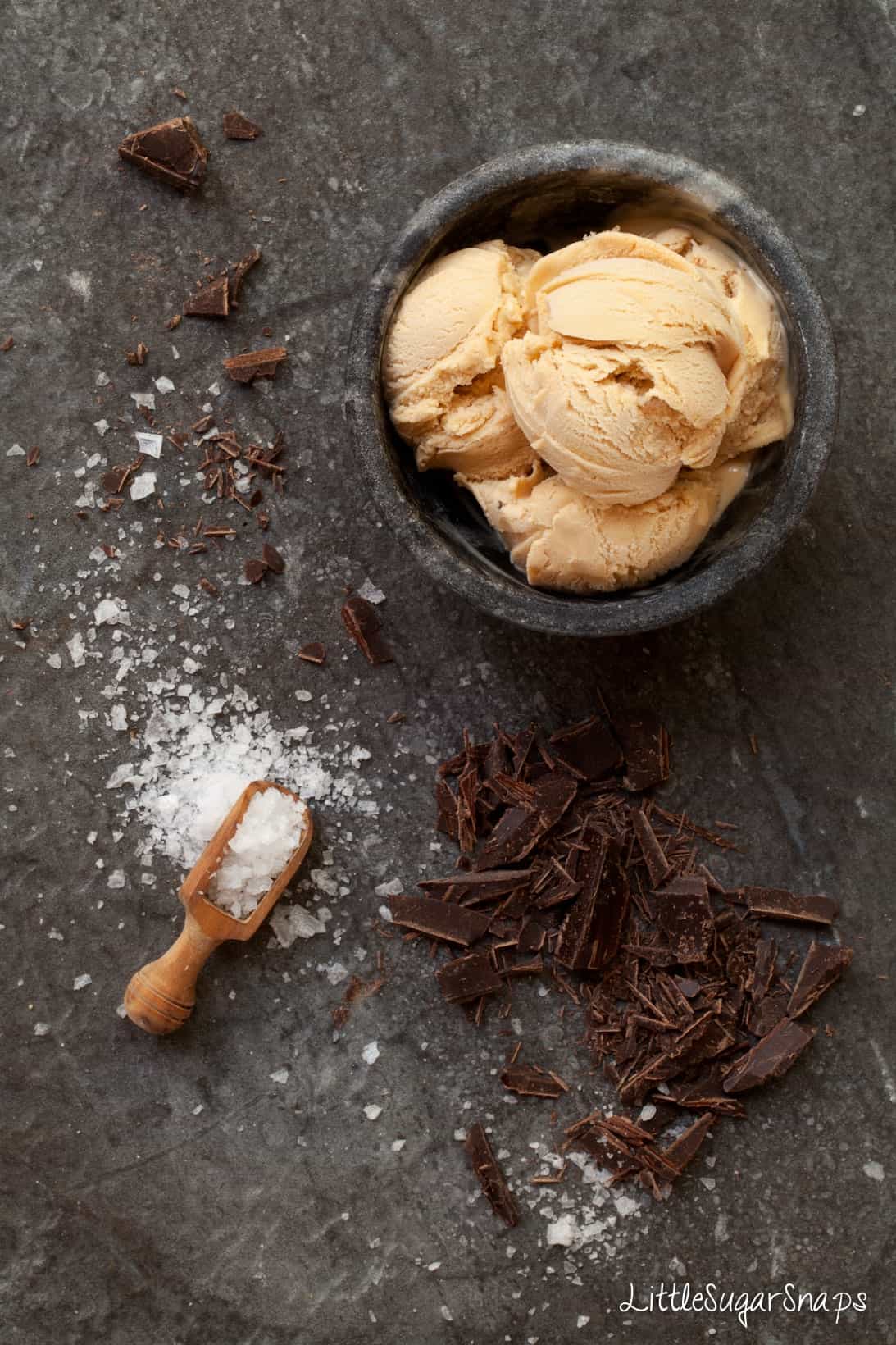 A bowl of salted caramel ice cream with dark chocolate and sea salt alongside