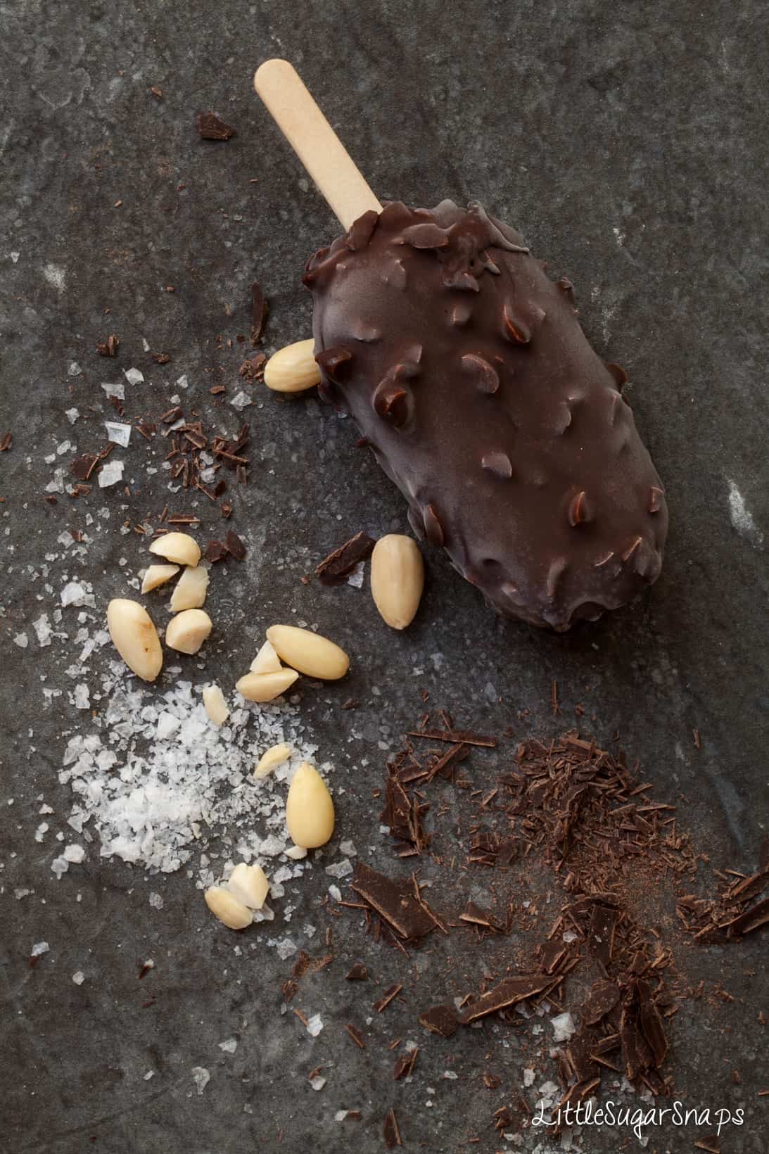 A chocolate covered ce Cream Bar with almonds, chocolate and seasalt alongside