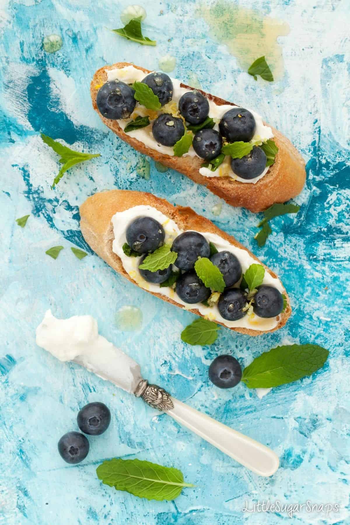 overhead of blueberries, mint, lemon and mascarpone cheese on toast