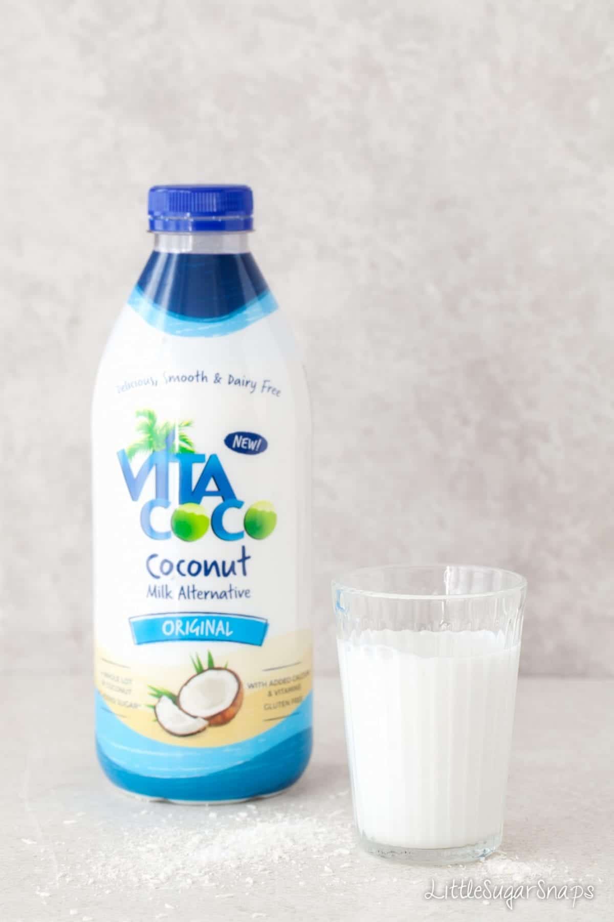 A glass of coconut milk next to a bottle