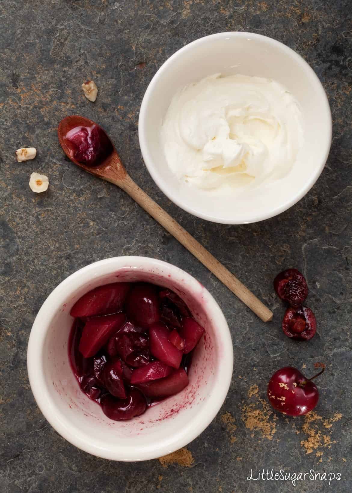 Red wine poached fruit and whipped cream in bowls.