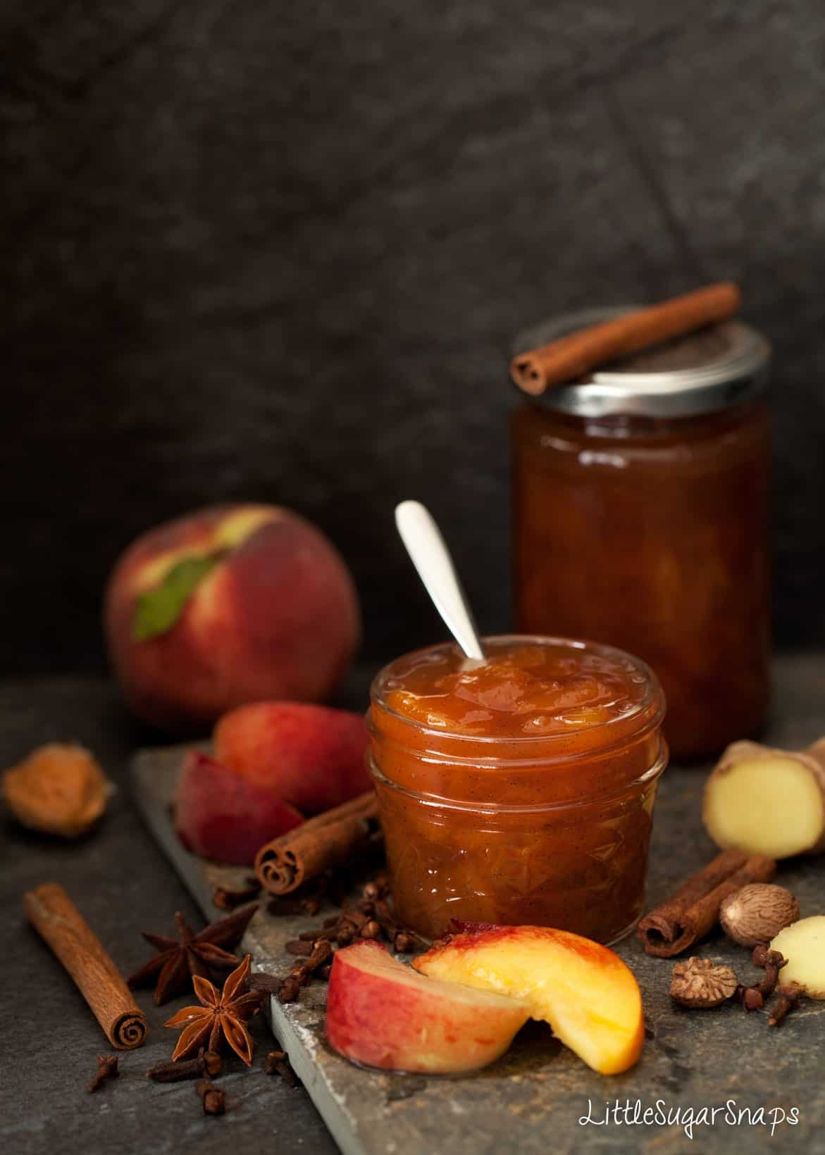 Spiced Peach Jam in a jar with ingredients alongside