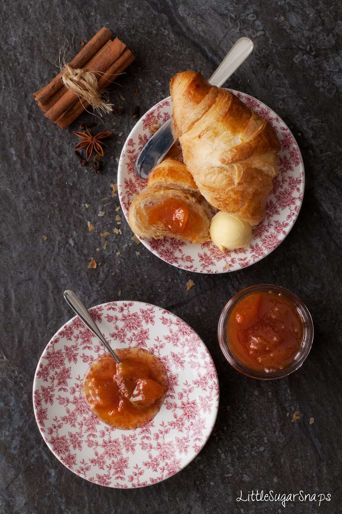 overhead of a jar of peach jam and a croissant