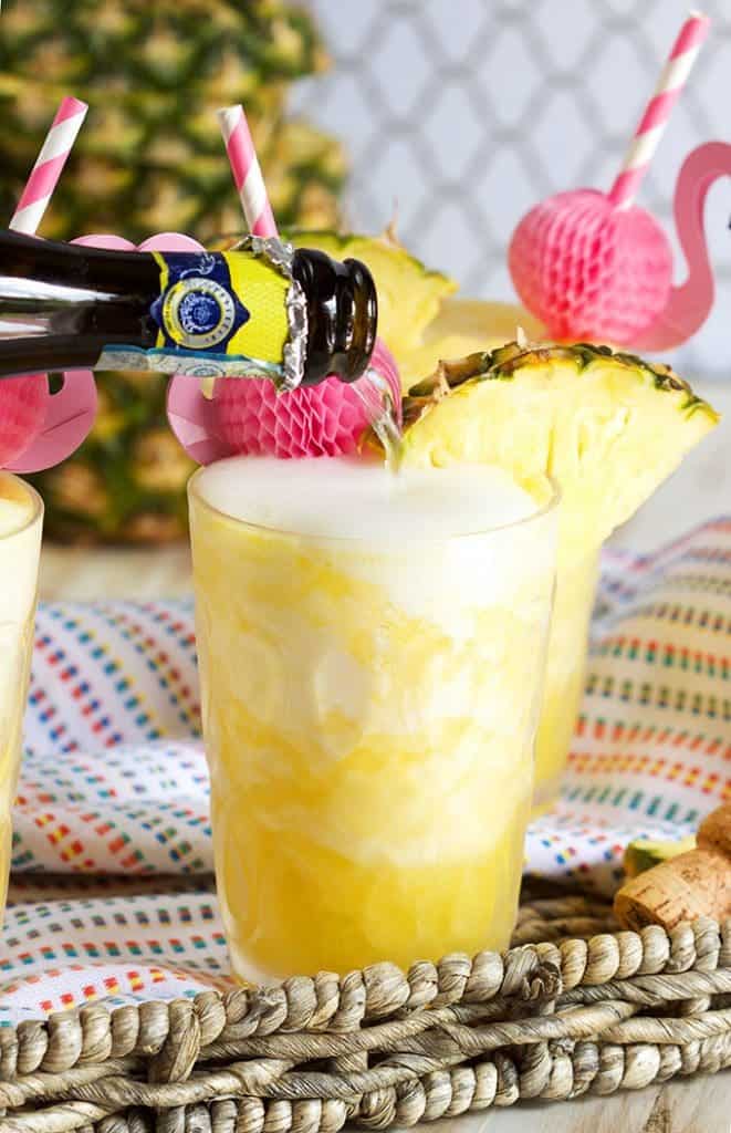 Person pouring Prosecco into a pineapple slushie drink