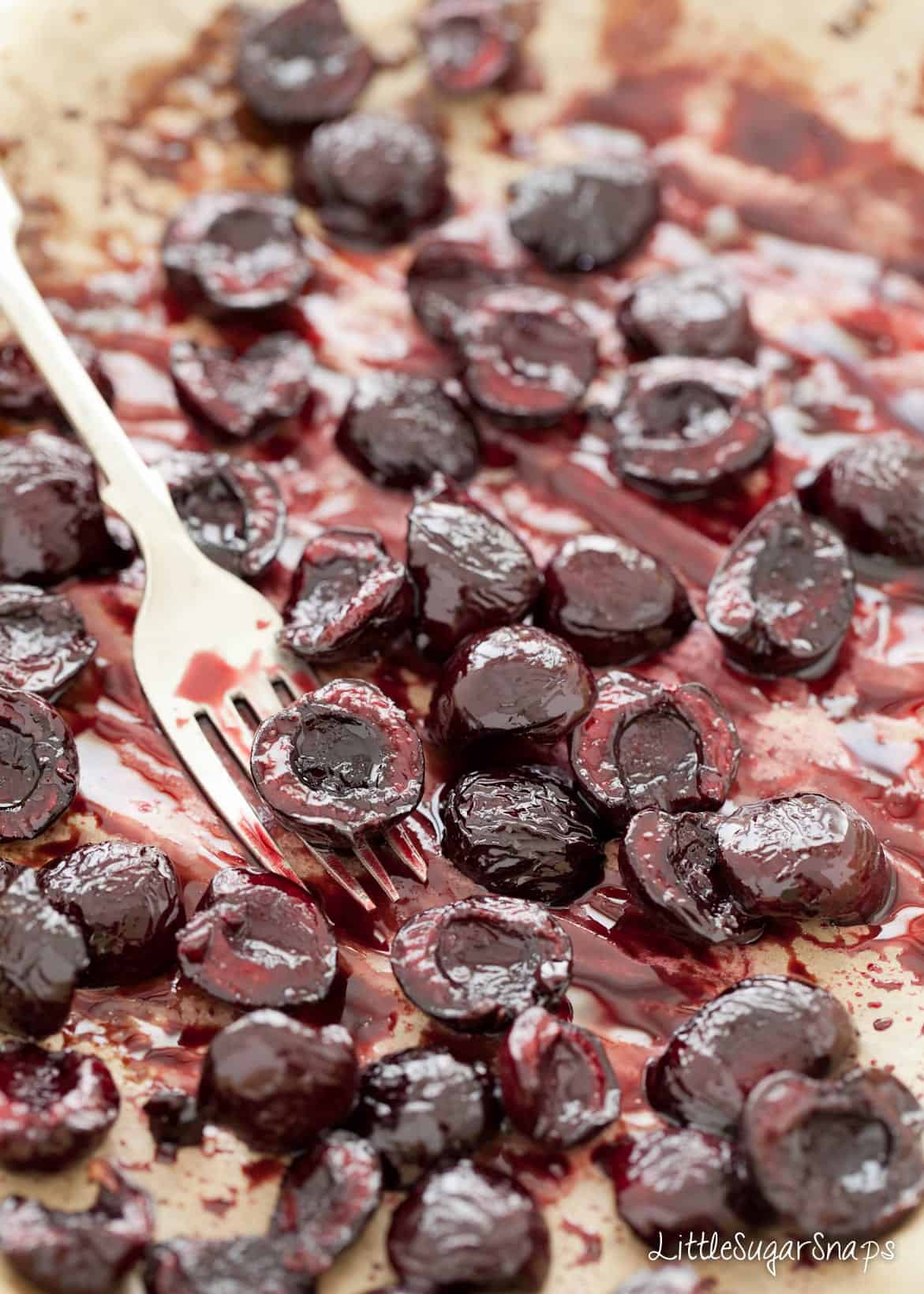 Close up of balsamic roasted Cherries on baking parchment.