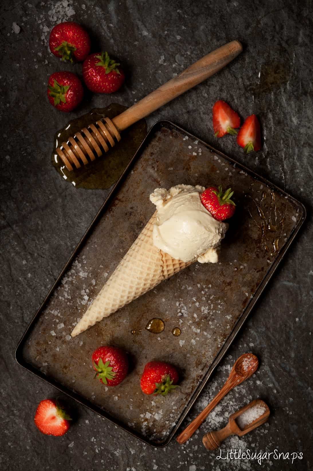 Honey ice cream in a waffle cone with a fresh strawberry on top