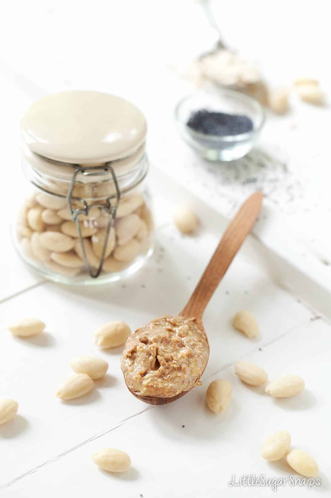 Almond butter and blanched almonds on a worktop.