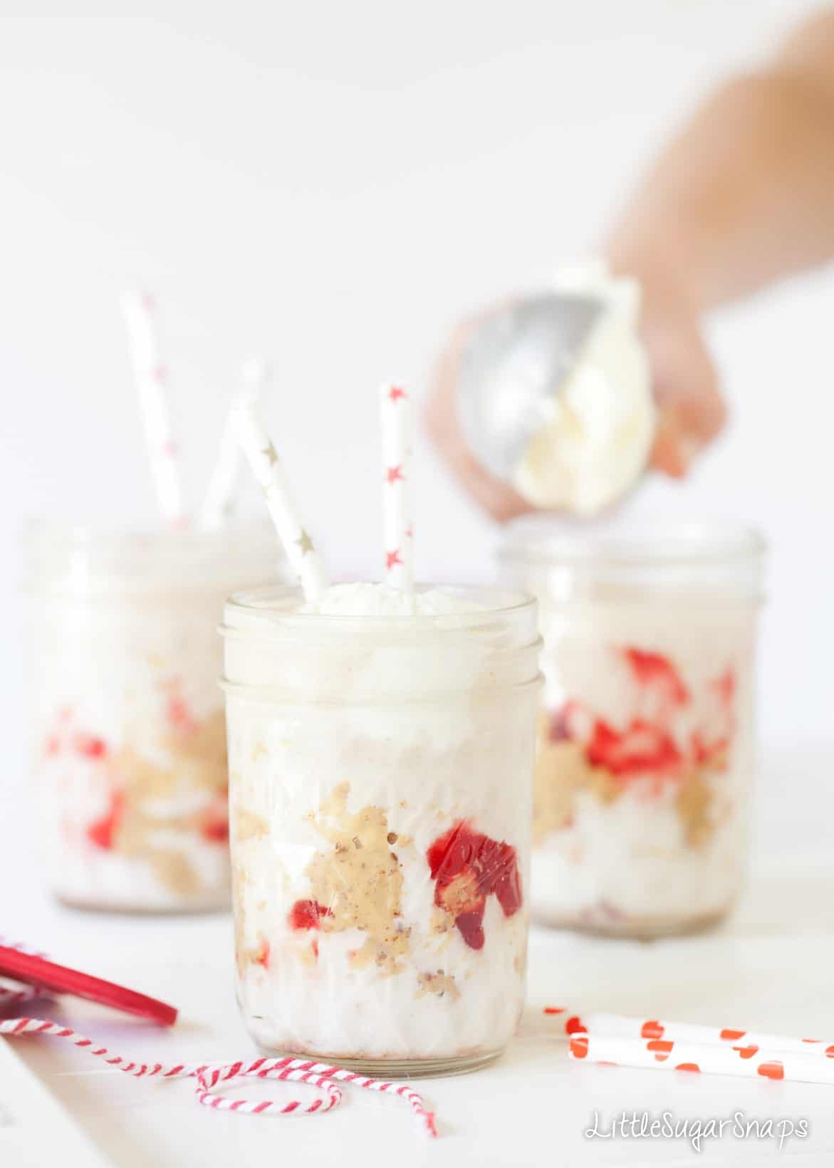 Person topping Peanut Butter and Jelly Milkshakes with ice cream.