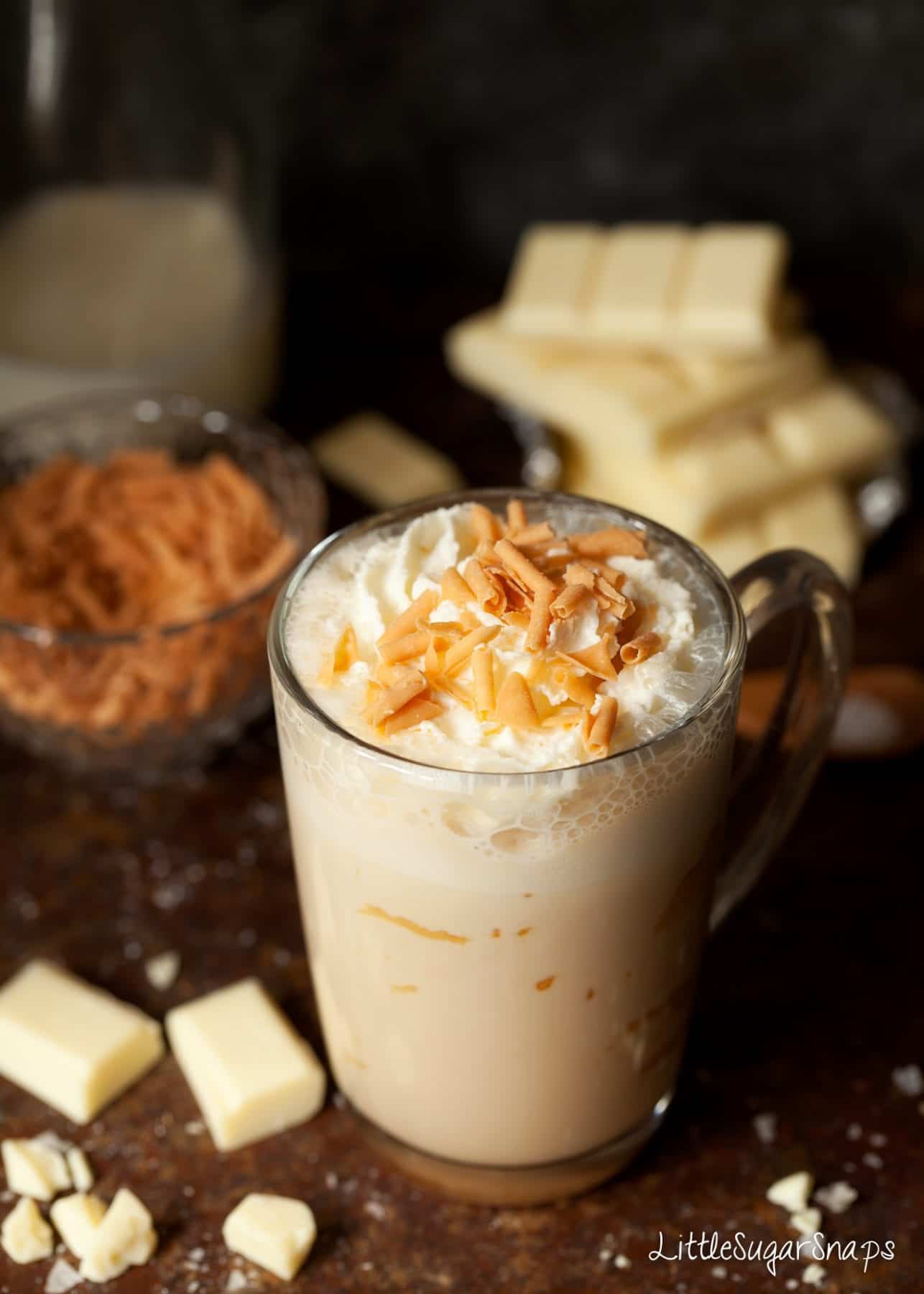 A mug of Caramelised White Hot Chocolate with cream and caramel flakes.