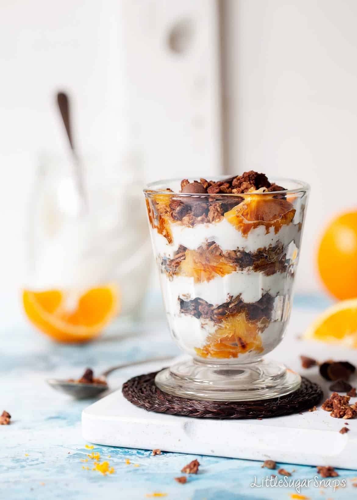 Layered parfait in a glass: fresh orange, yoghurt and chocolate granola