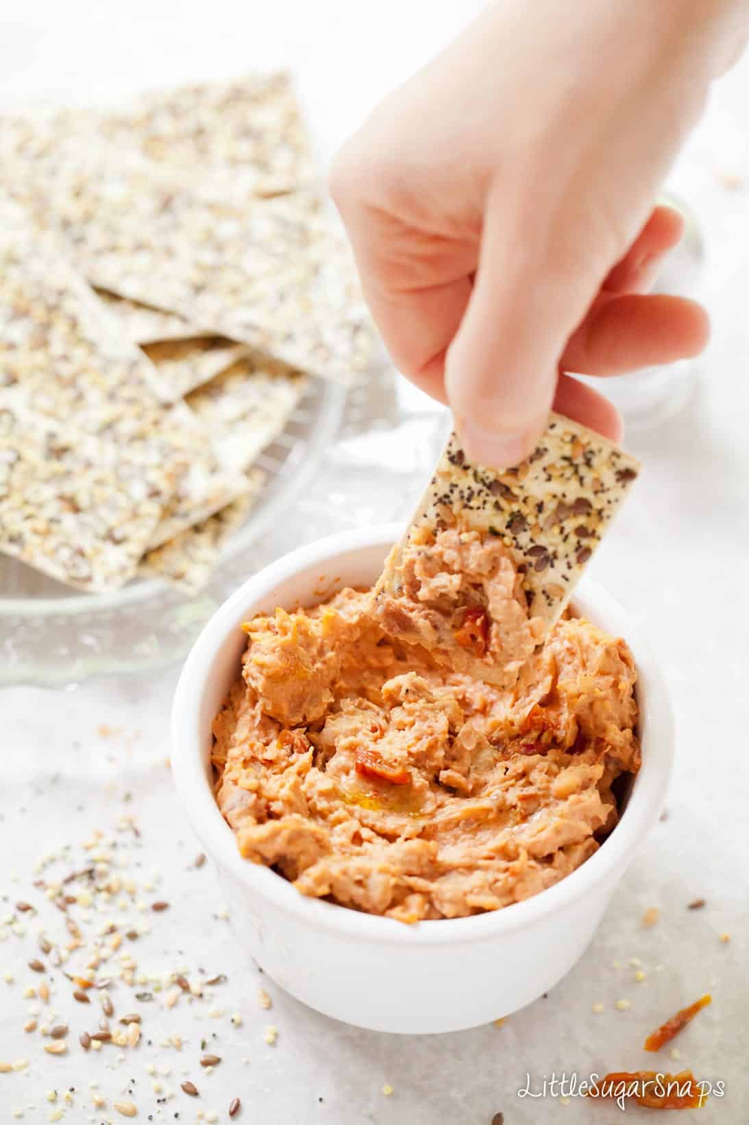 Person dipping a cracker into a bowl of White Bean Dip