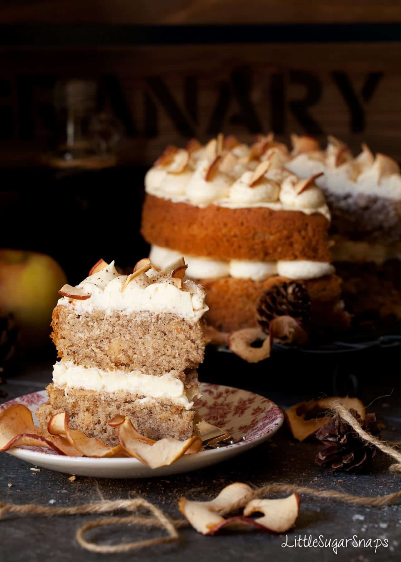 A slice of cinnamon apple cake with maple buttercream on a red side plate.