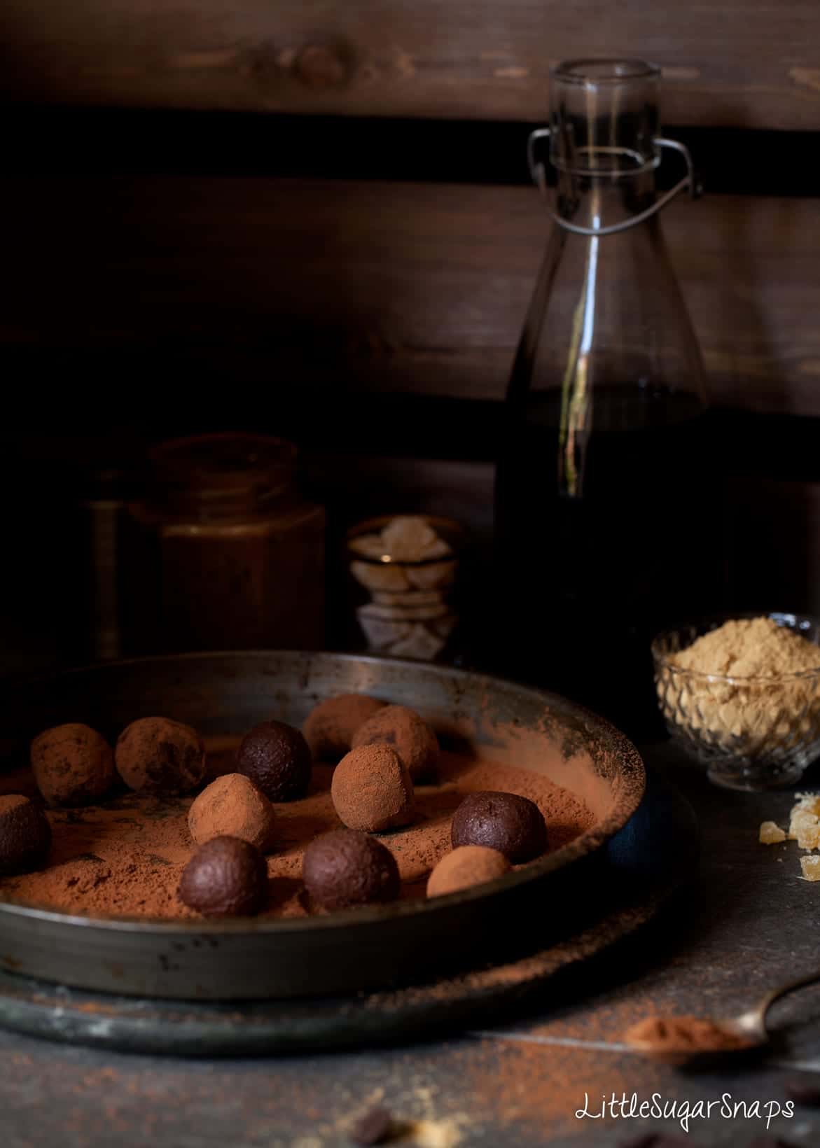 Chocolate truffles being rolled in sieved cocoa powder.