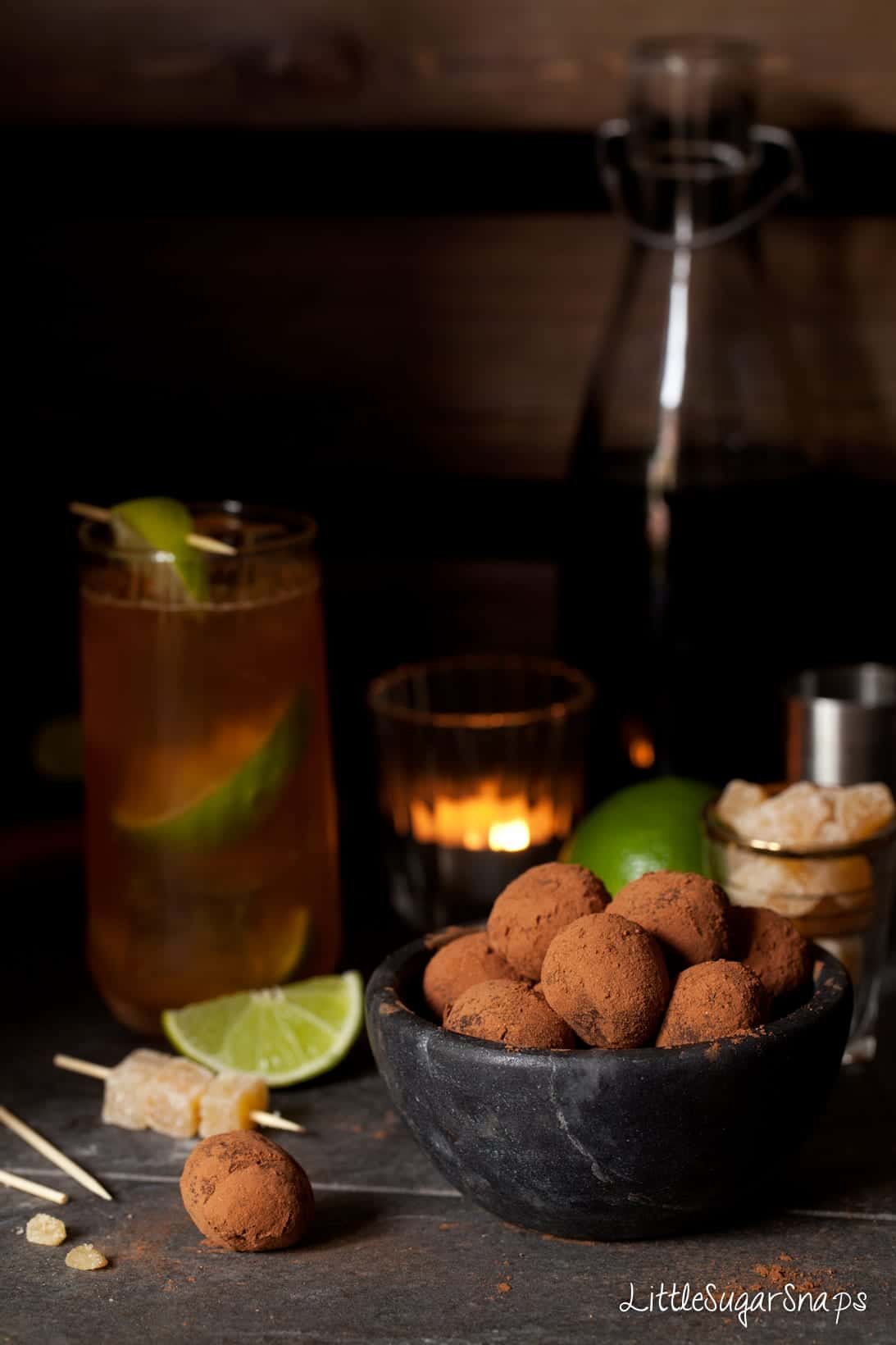 Ginger Truffles in a black bowl with a Dark n Stormy cocktail behind it.