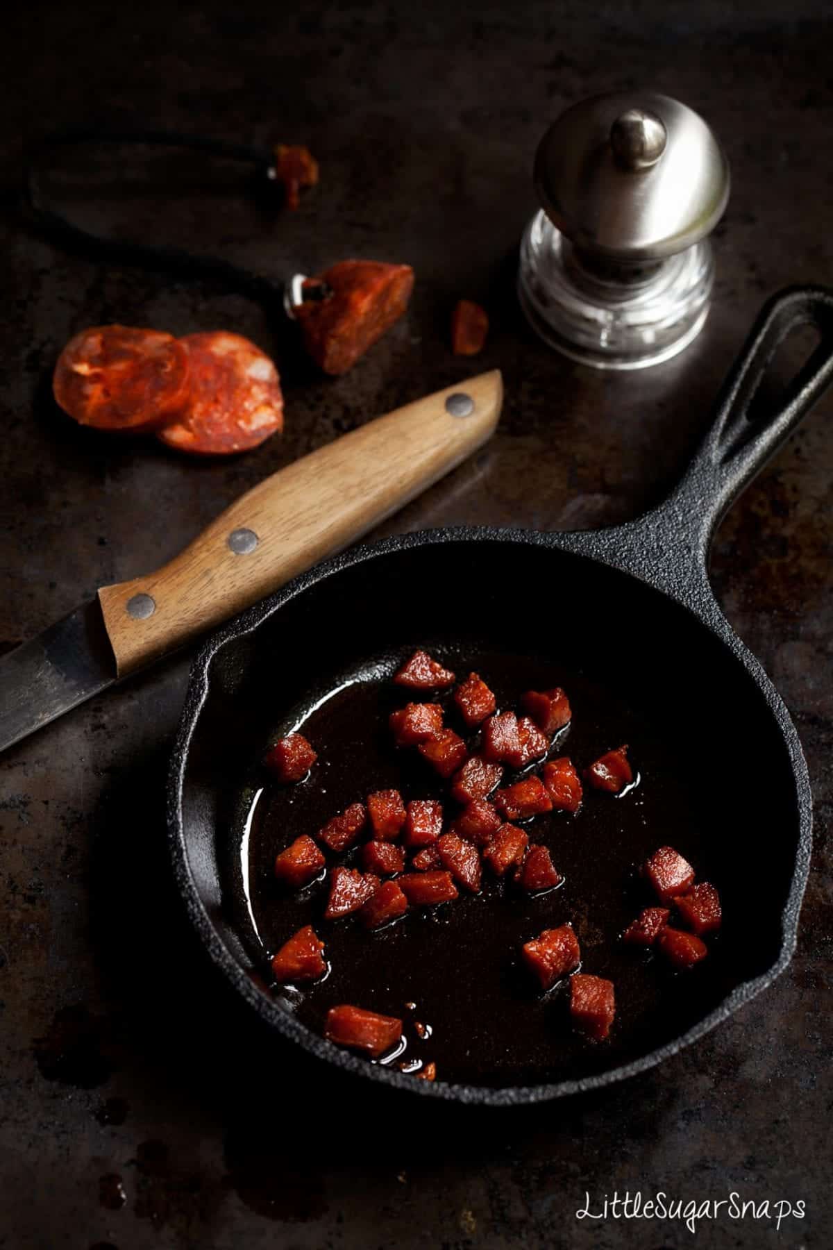 Freshly cooked chunks of chorizo in a small cast iron skillet pan. 