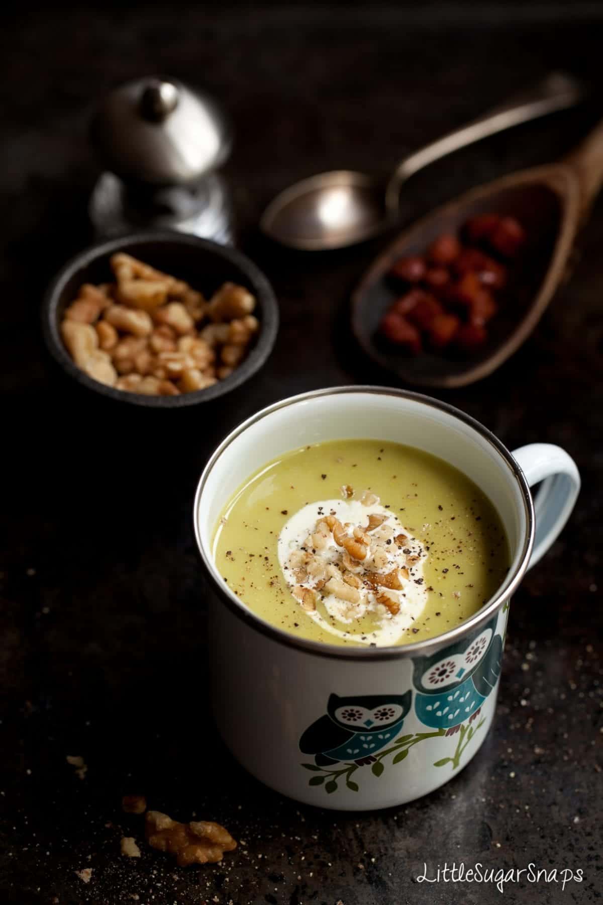 Spinach and stilton soup in an owl design enamel mug with cream and walnut garnish.