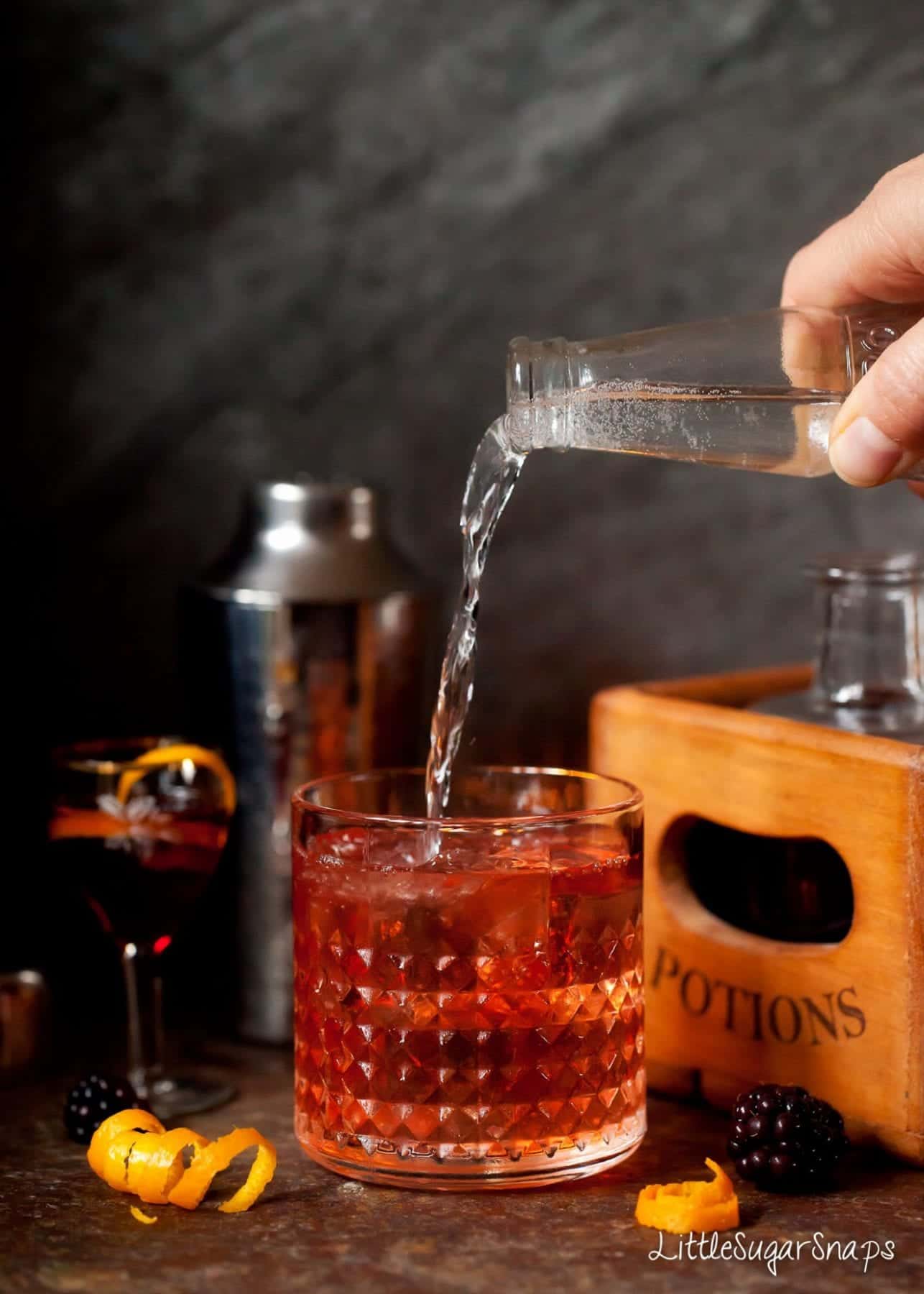 Person pouring a Winter Gin & Tonic made with sloe gin.