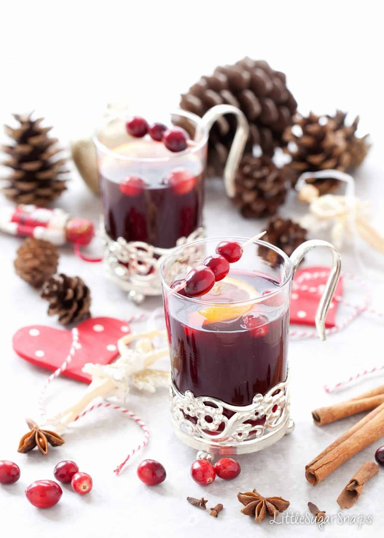 Two glasses of Mulled Grape Juice garnished with cranberries and orange slices.