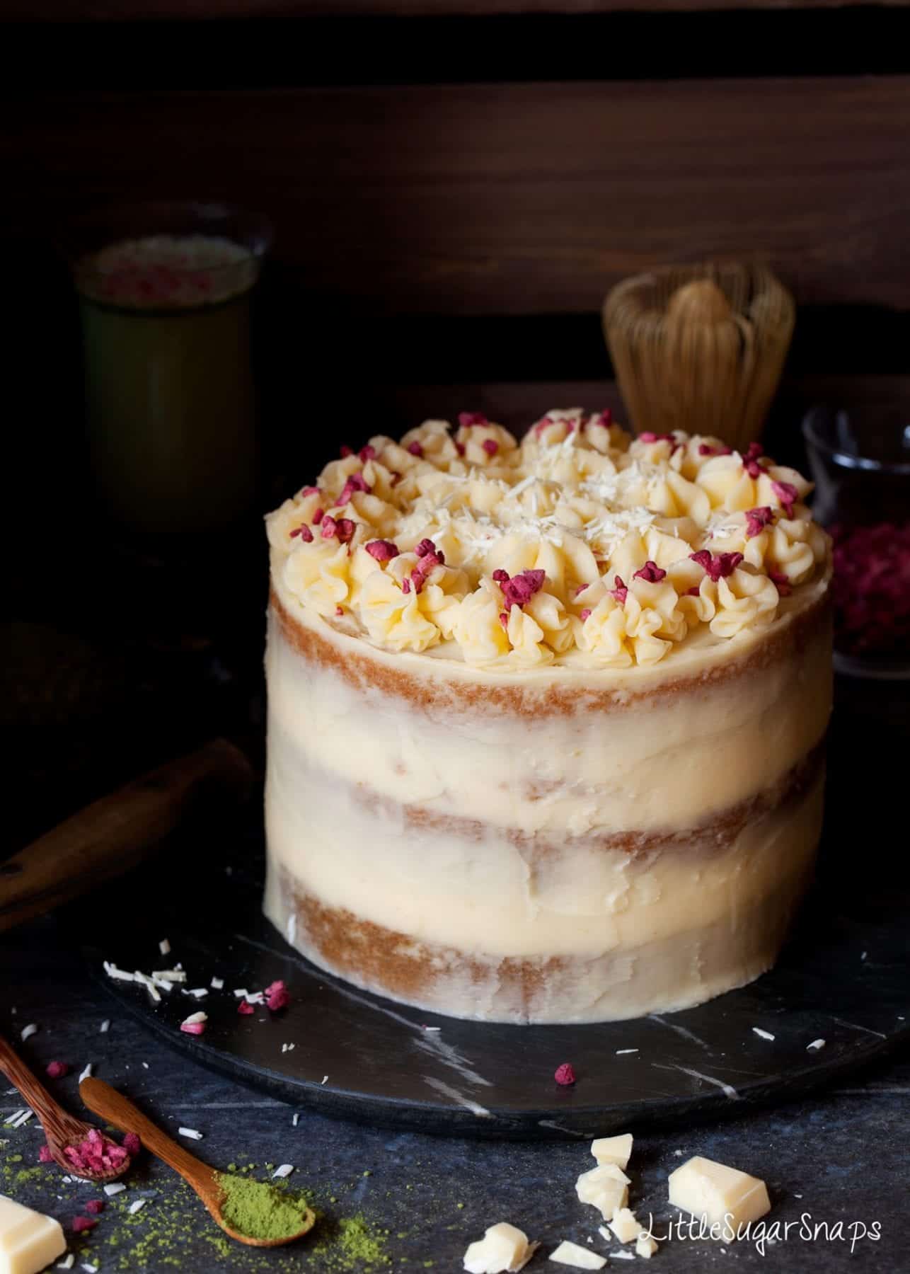 A naked style layer cake topped with freeze dried raspberries and grated white chocolate.