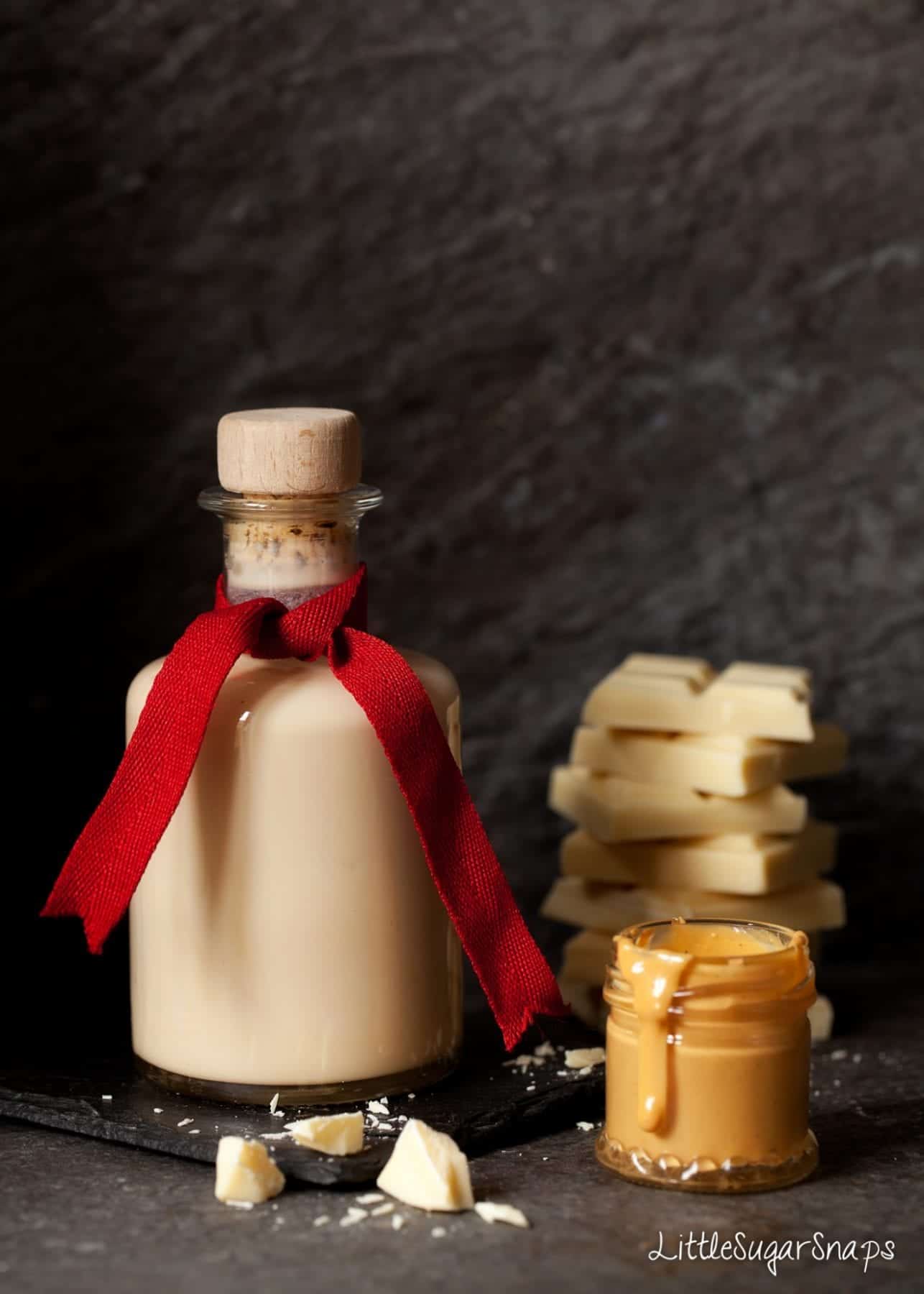 A bottle of homemade chocolate cream liqueur with ingredients at the side