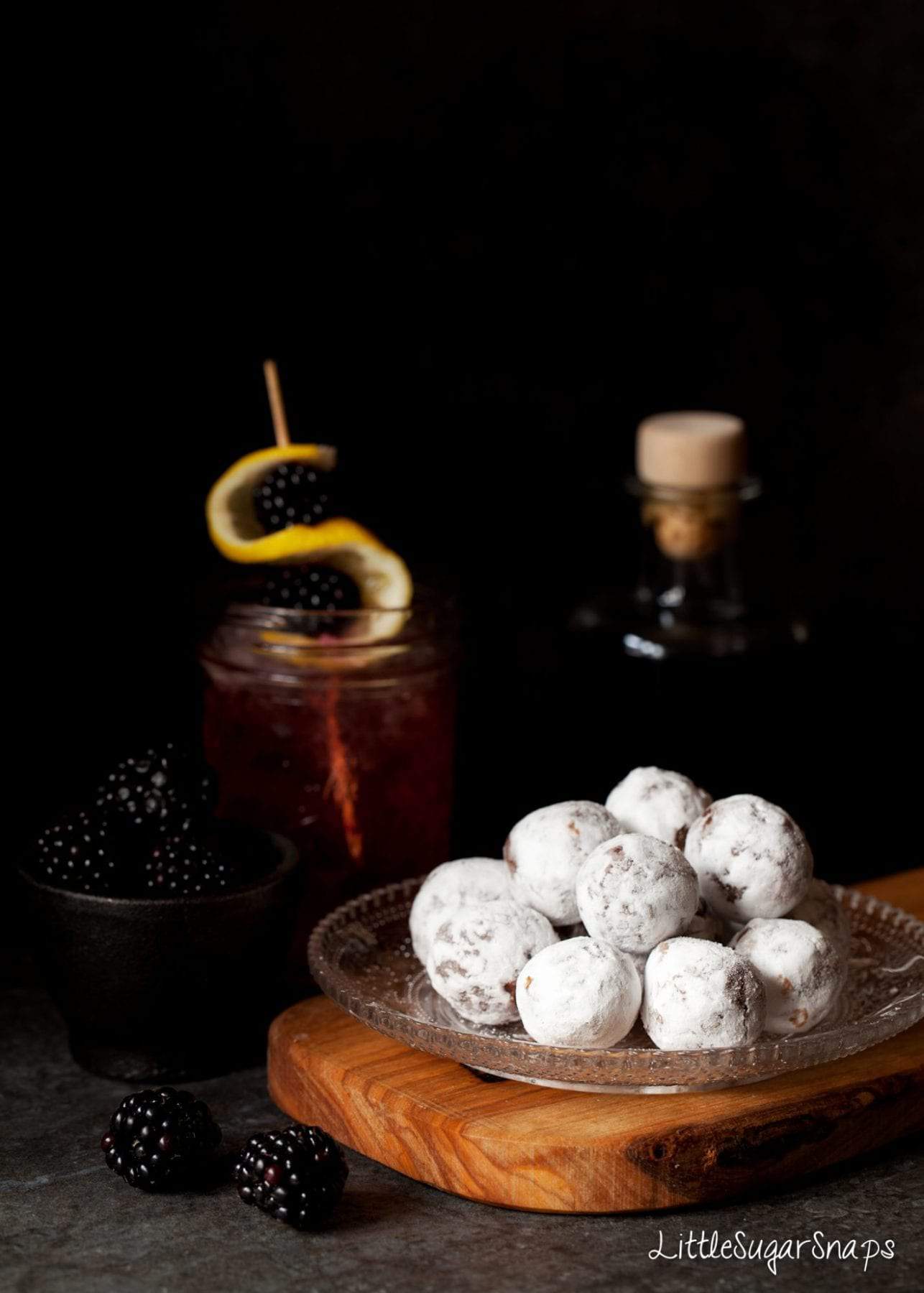 A plate filled with Bramble Truffles covered in icing sugar.