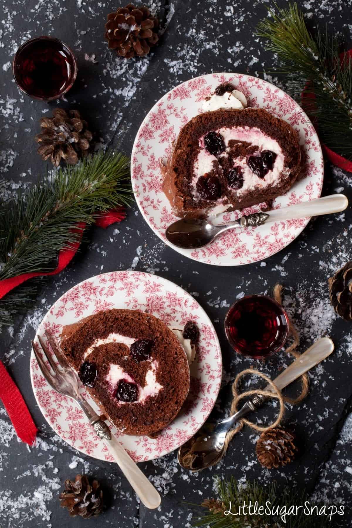 Slices of chocolate and cherry yule log cake on plates.