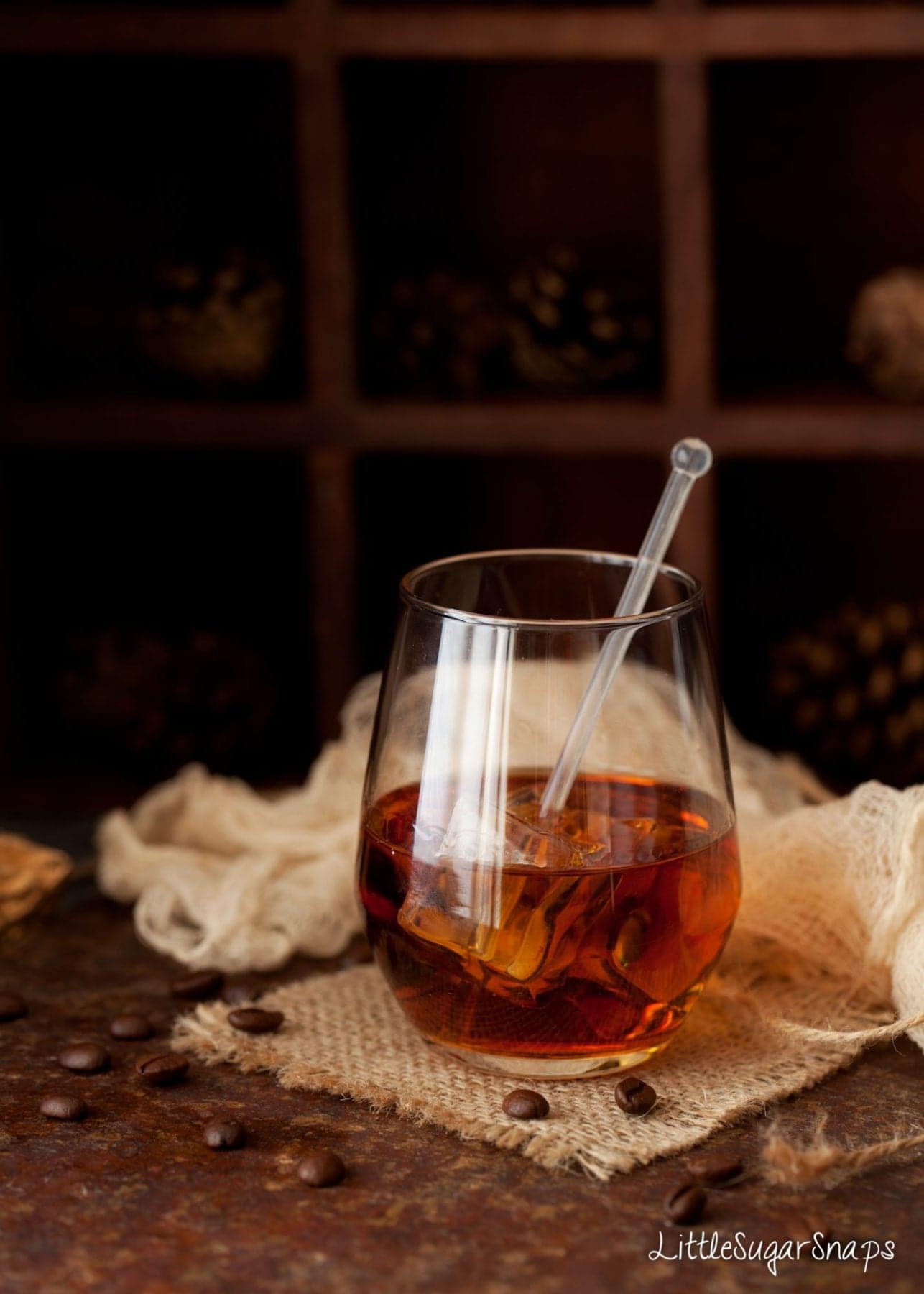 Black Russian cocktail in a glass with coffee beans scattered around