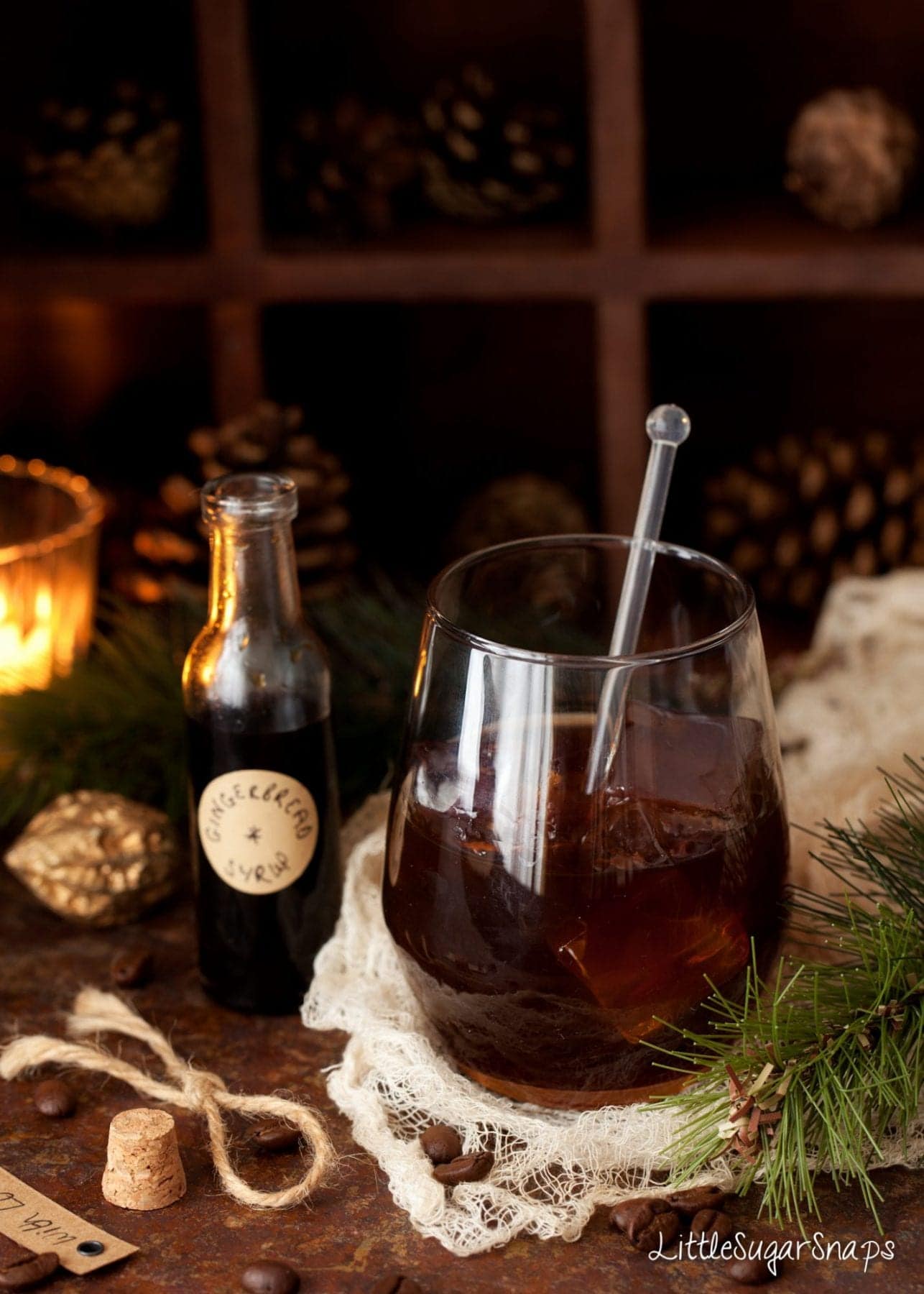 A gingerbread black Russian cocktail with a miniature bottle of gingerbread syrup alongside.