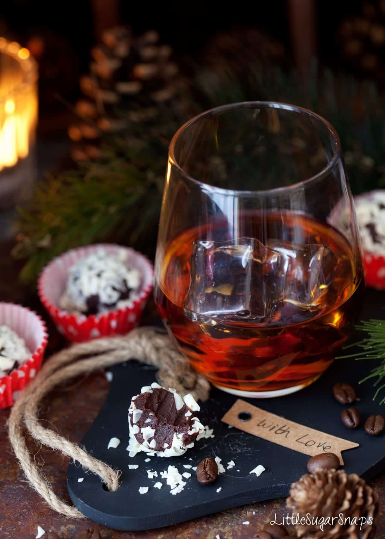 A bitten into Black Russian Truffle with a black russian cocktail served next to it.