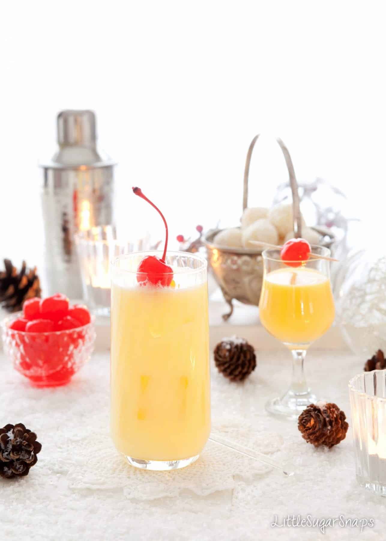 A classic snowball cocktail and a glass of Advocaat. Both are garnished with cocktail cherries.