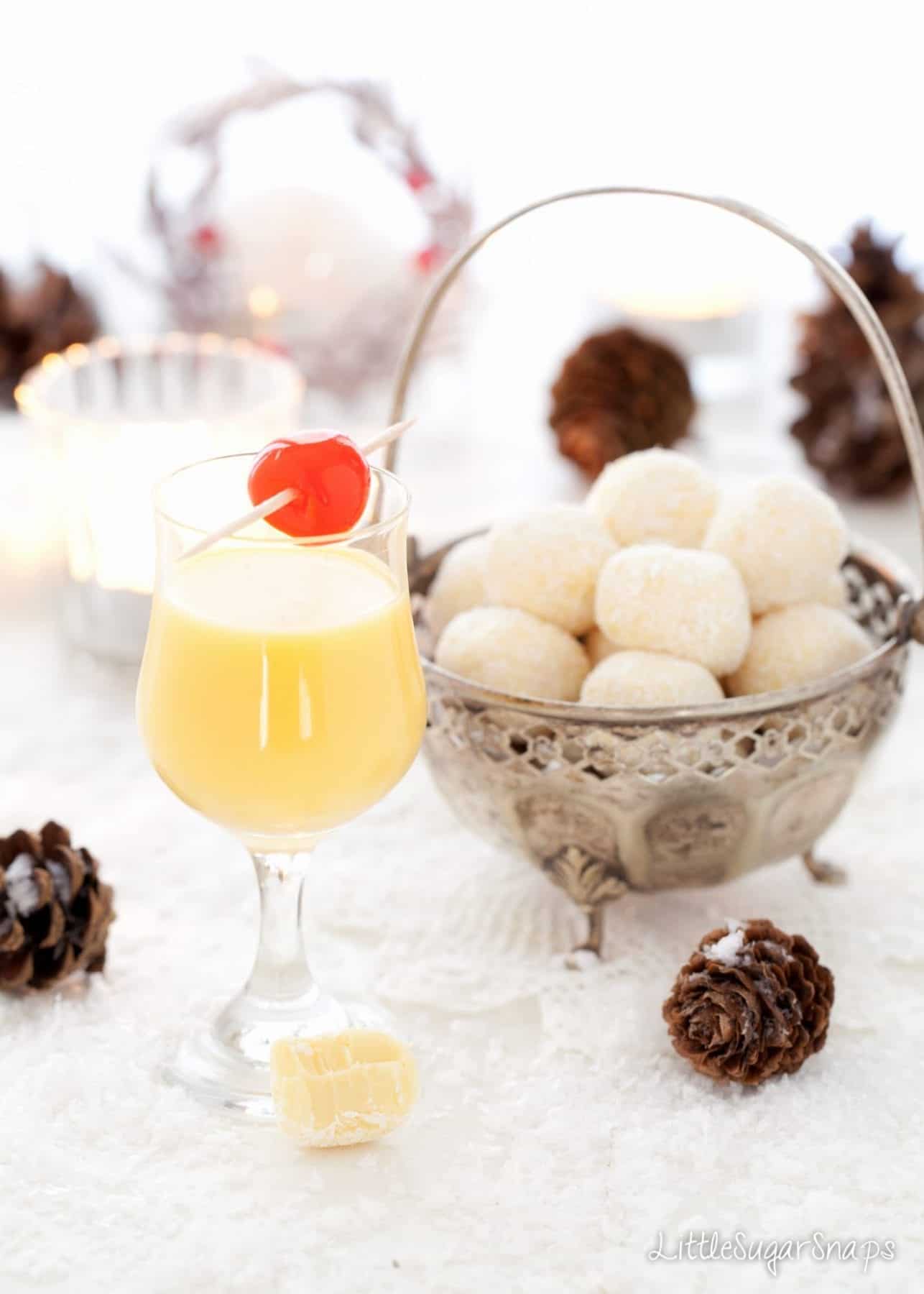 A glass of advocaat next to a bowl of Snowball Truffles