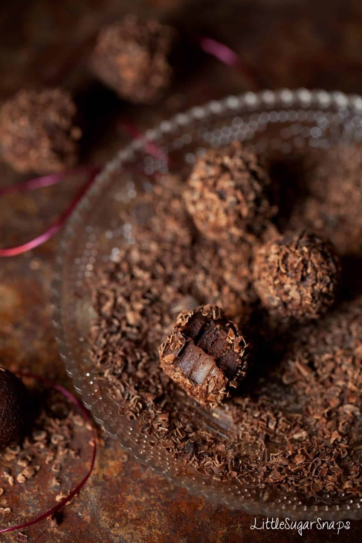 A bitten into homemade chocolate on a plate covered in chocolate flakes.