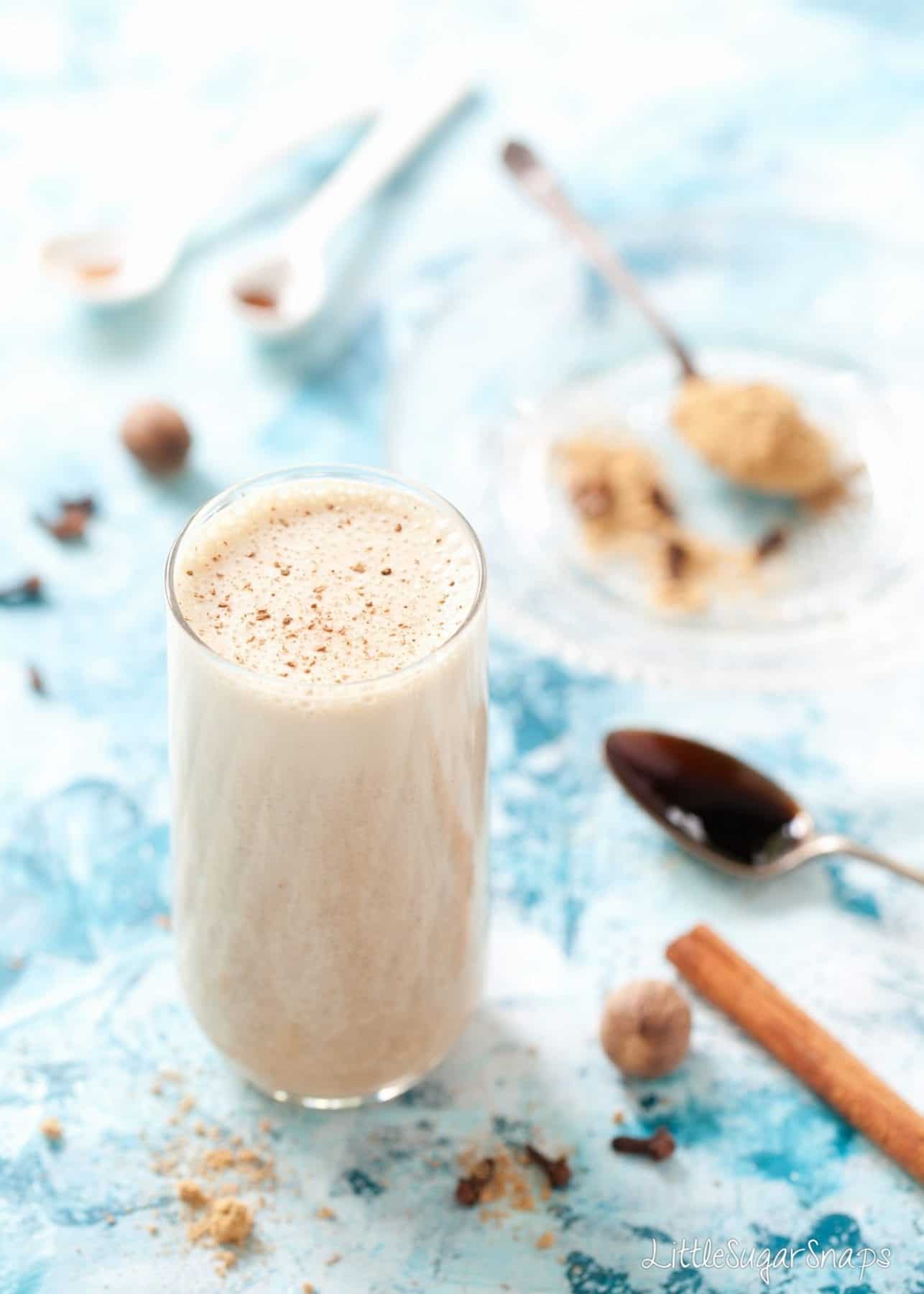 Gingerbread Date Shake in a tall glass with spices alongside.