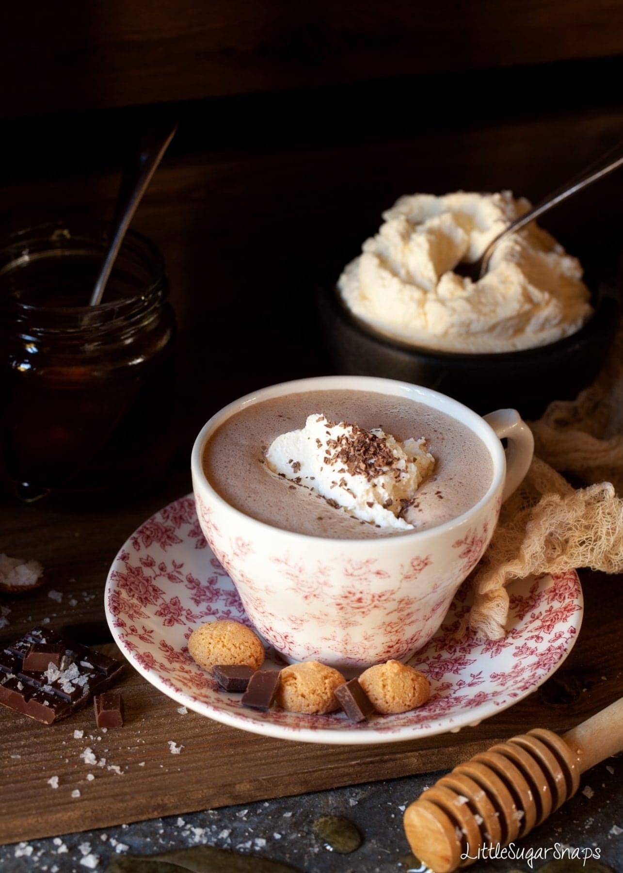 A cup of hot chocolate with cream, chocolate and amaretti cookies.
