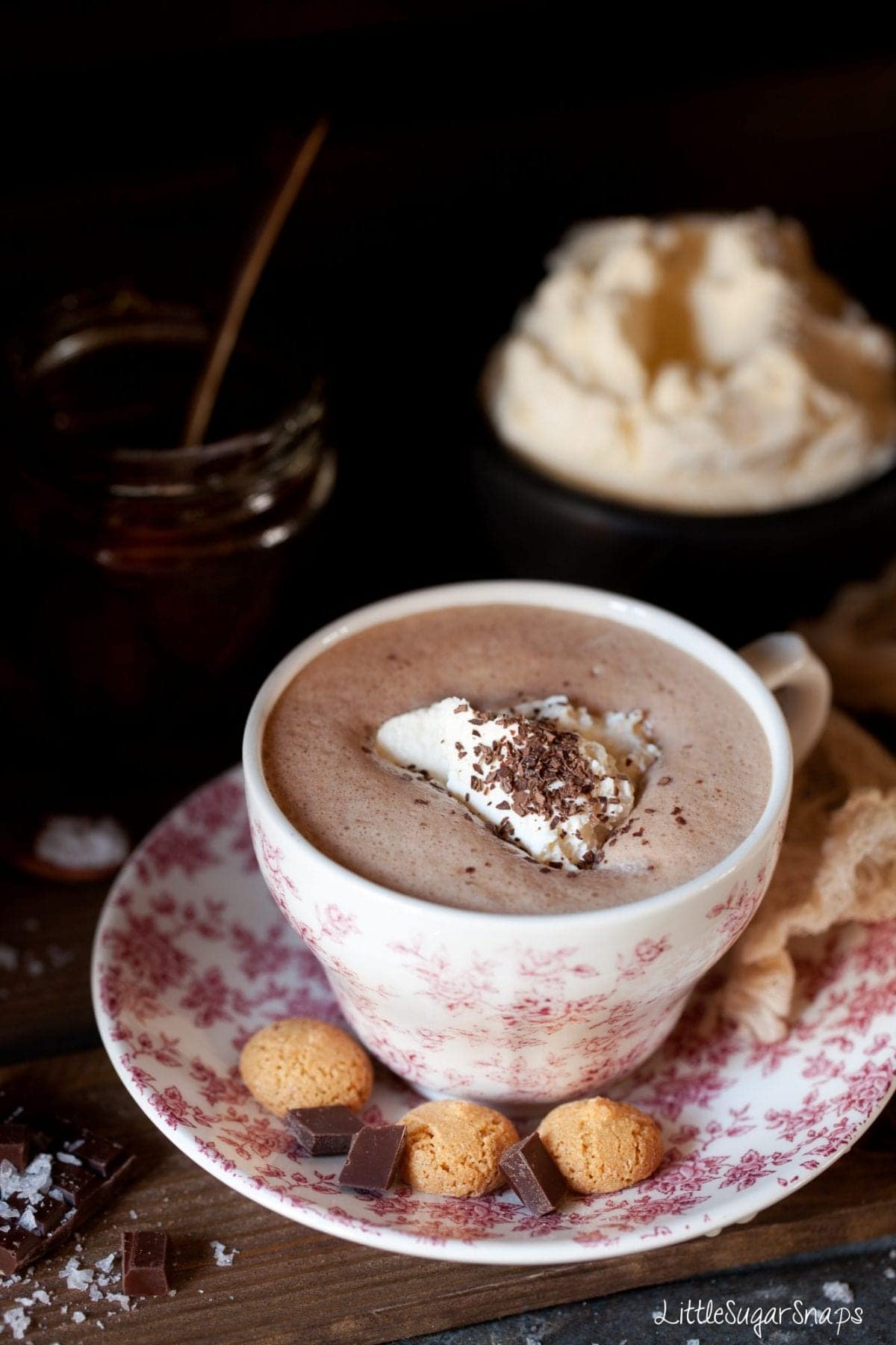 A cup of salted honey flavour hot chocolate with cream and amaretti cookies. 